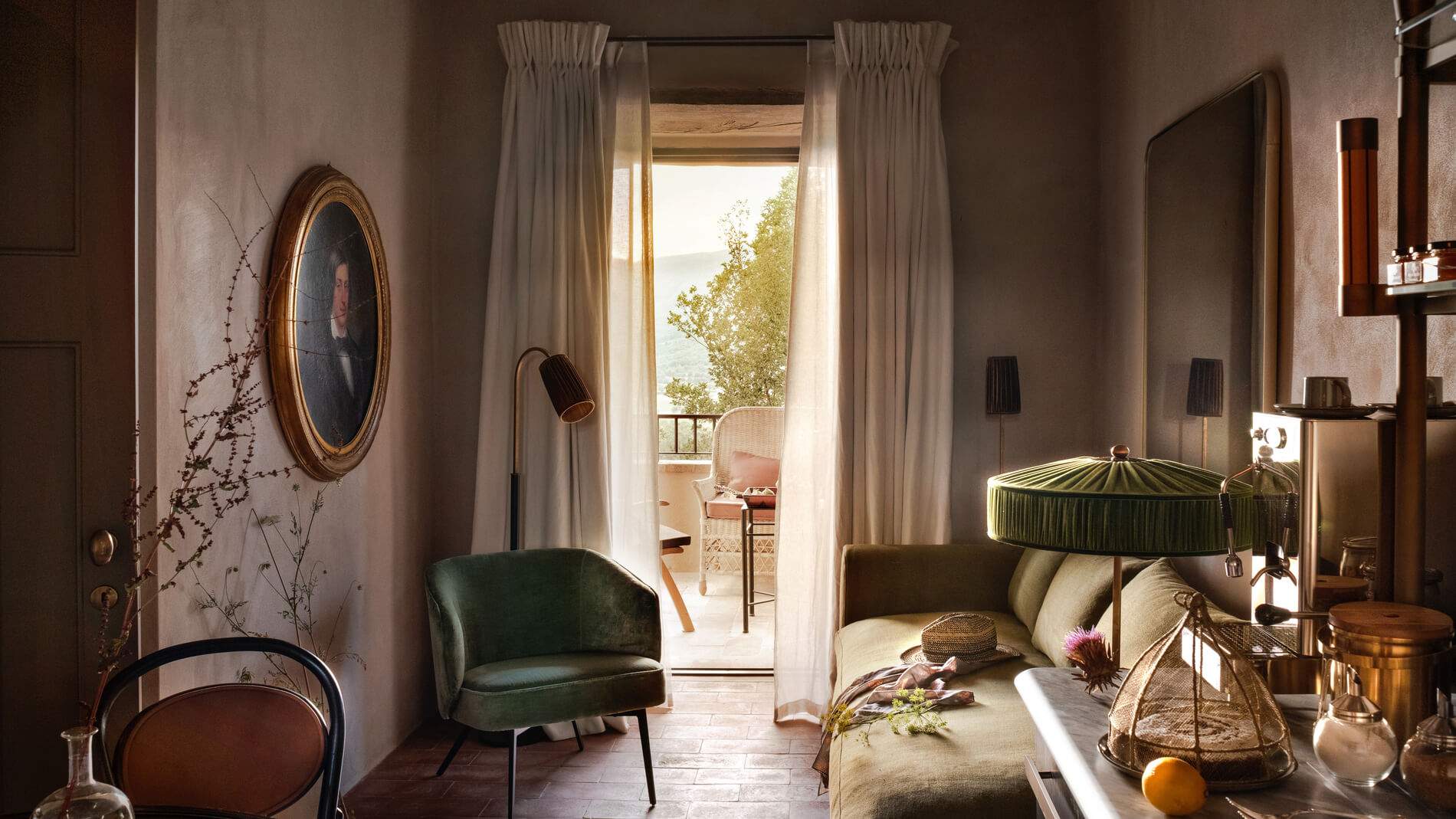 A living room with a green couch, a chair, a lamp, and a painting.