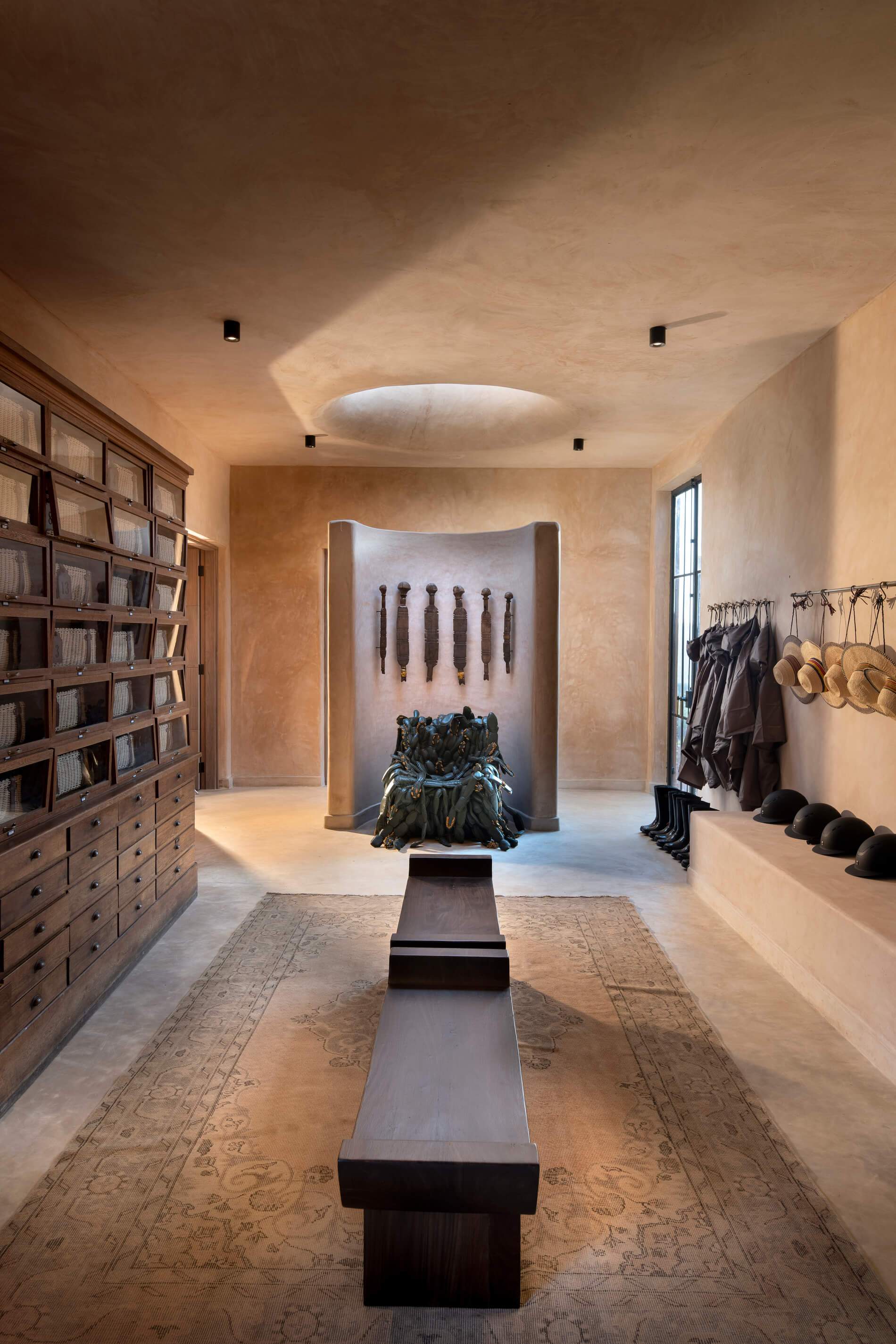 A room with a wooden bench and a wall of hats.
