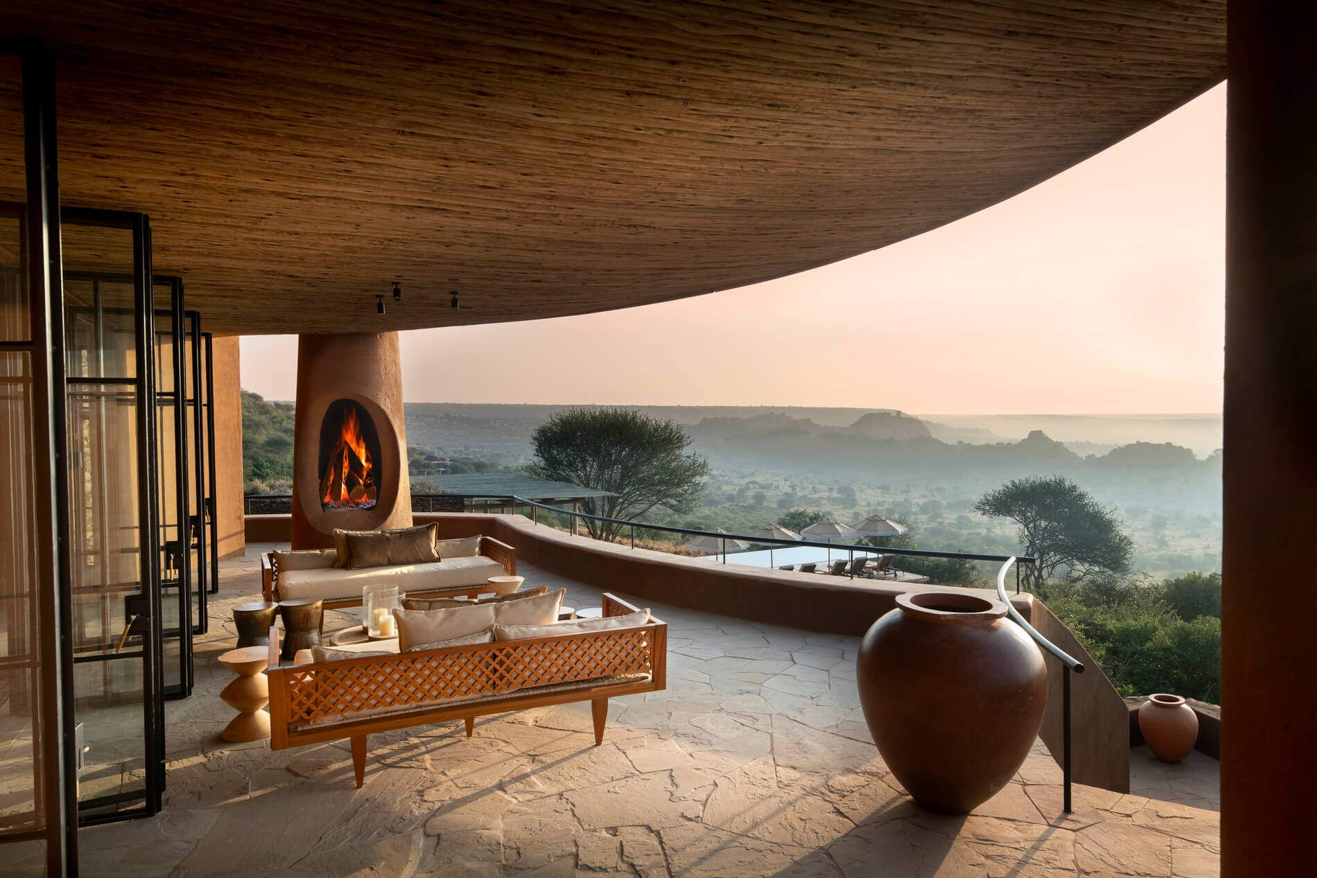 A brown vase sits on a stone patio near a fireplace.