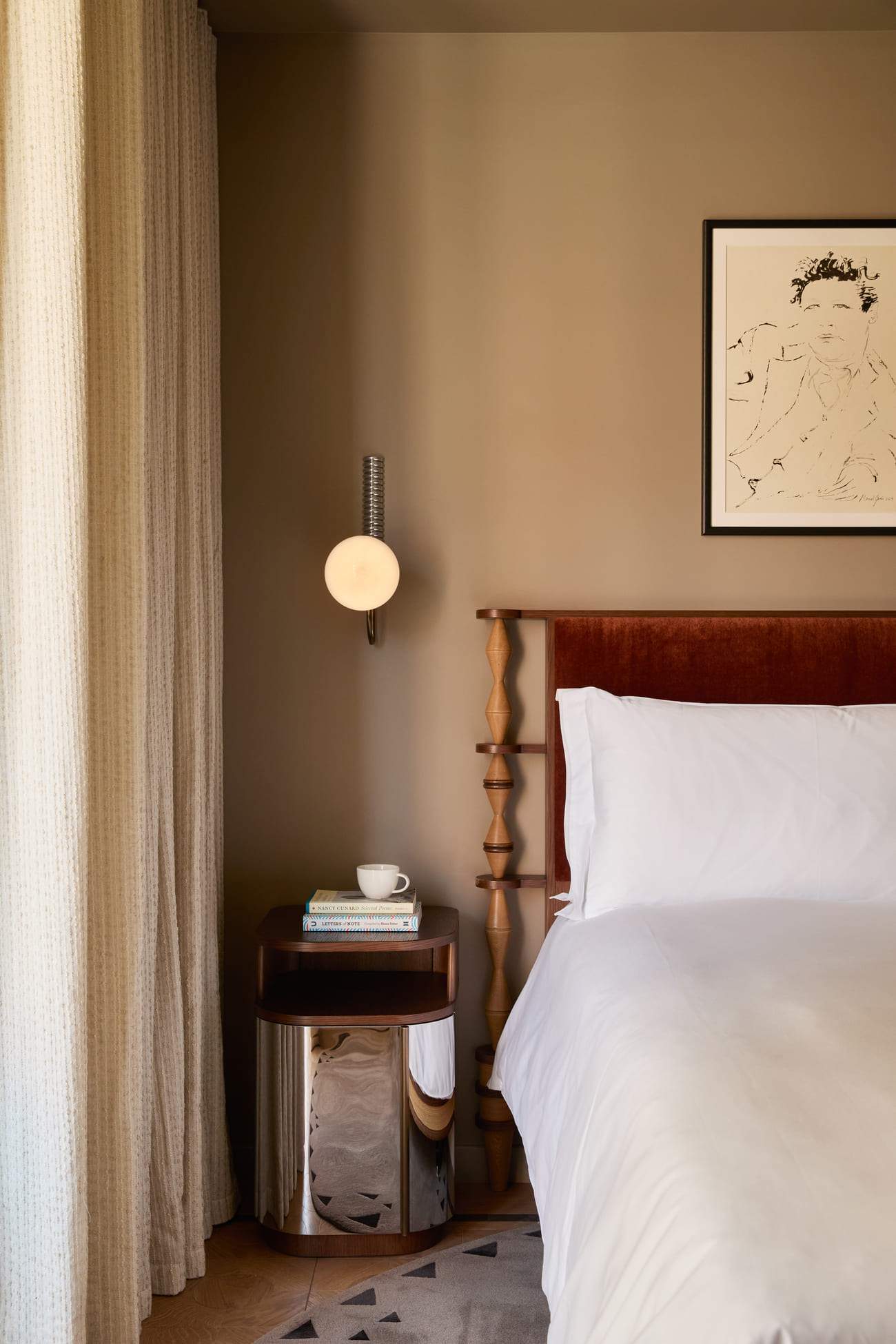 A bed with a white comforter and a picture of a man on the wall.
