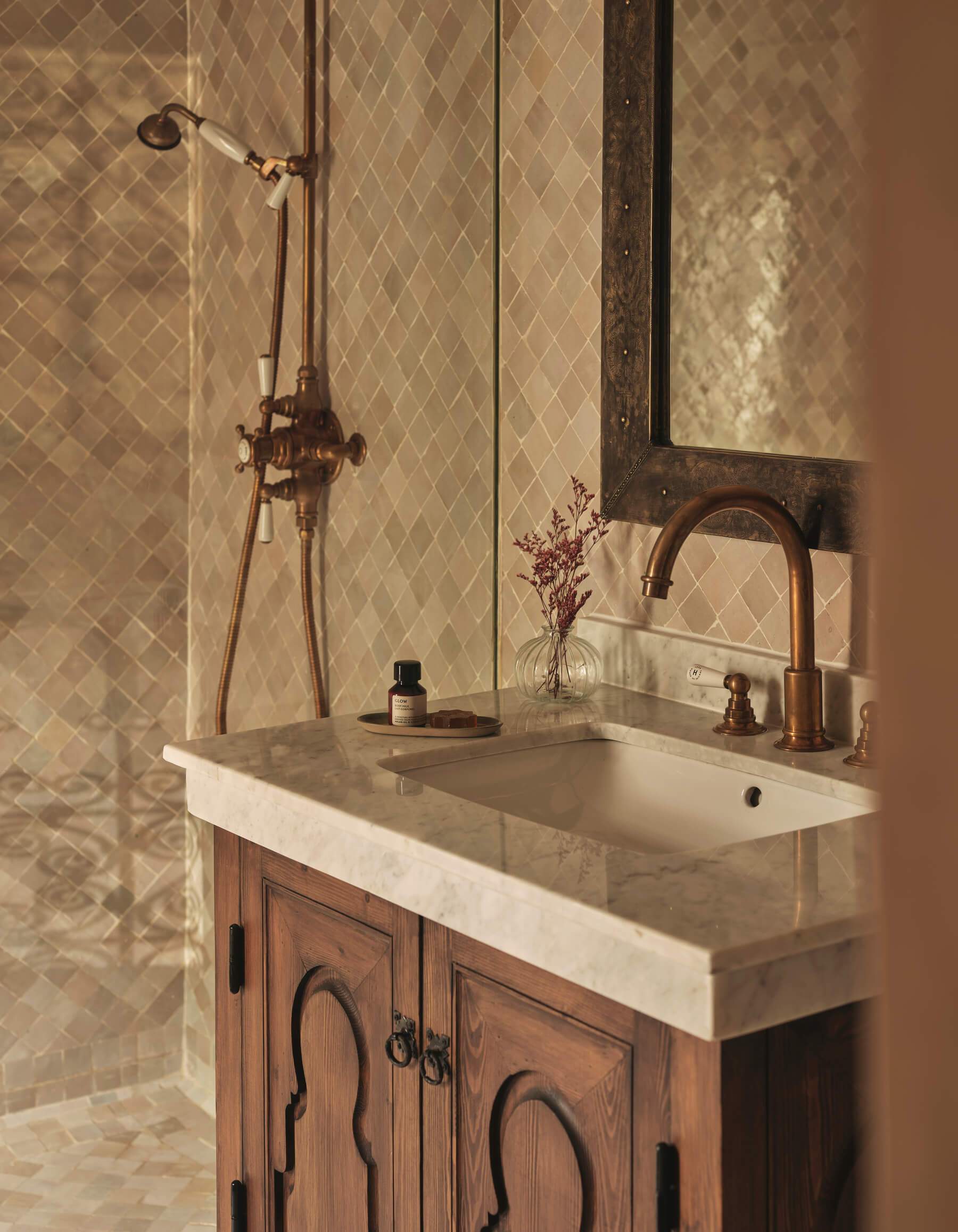 A bathroom sink with a gold faucet and a mirror above it.