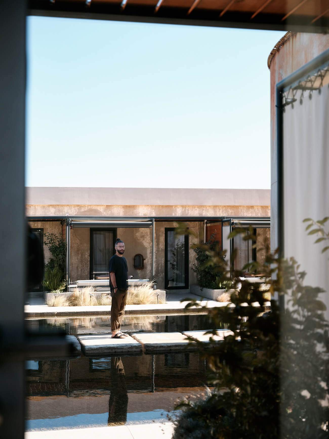 A man standing in front of a building with a pond in the background.
