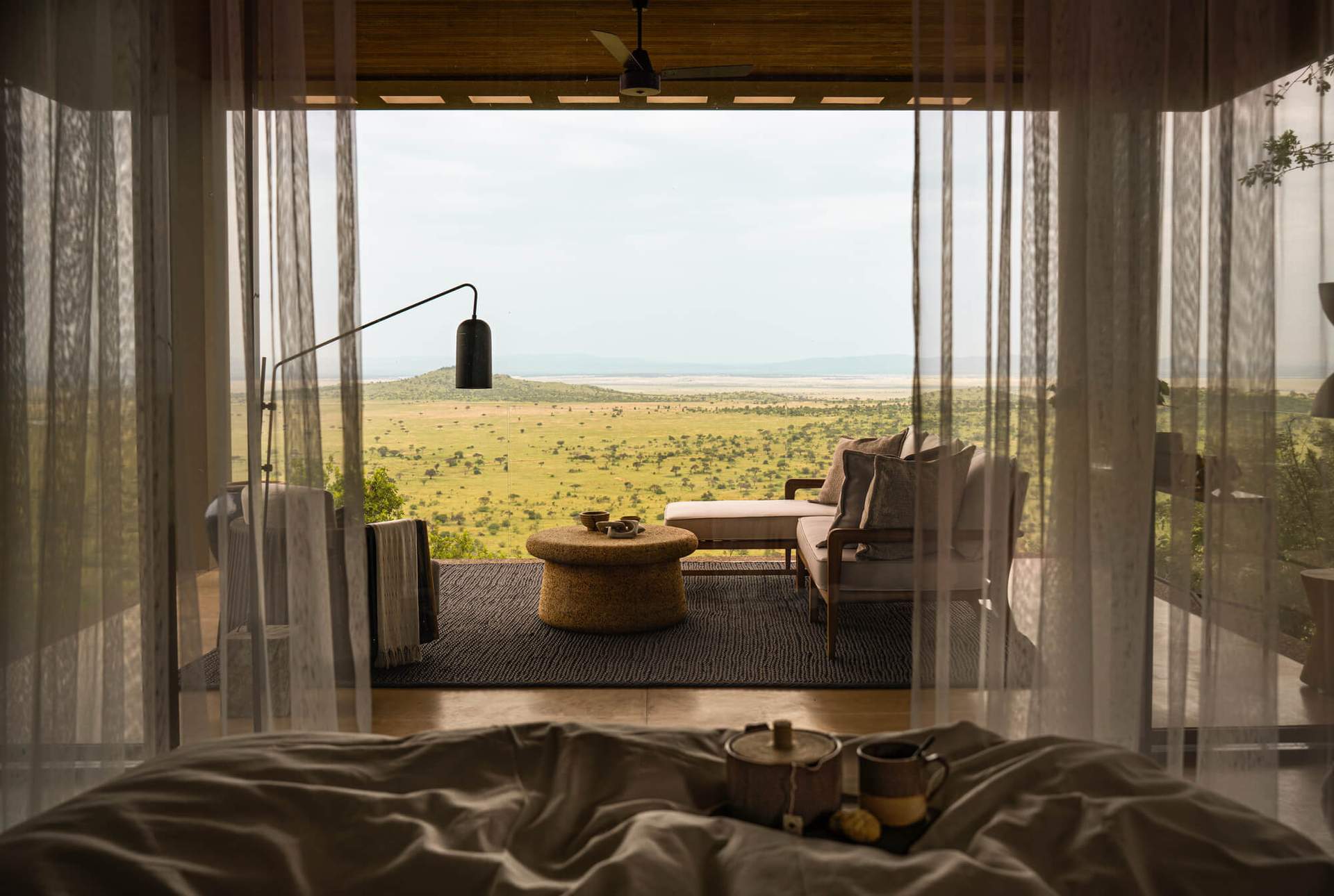 A bedroom with a bed and a table with a lamp and a cup on it.