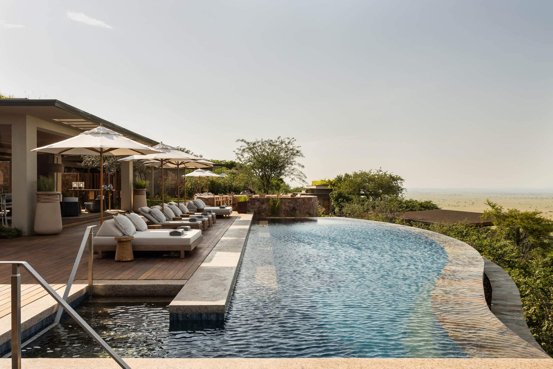 A large swimming pool with a wooden deck and a few umbrellas.
