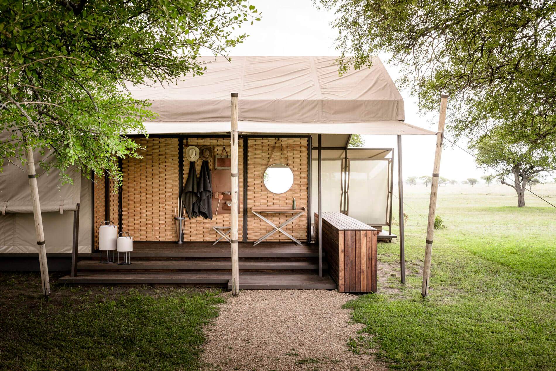 A small wooden house with a tarp roof and a table and chairs outside.