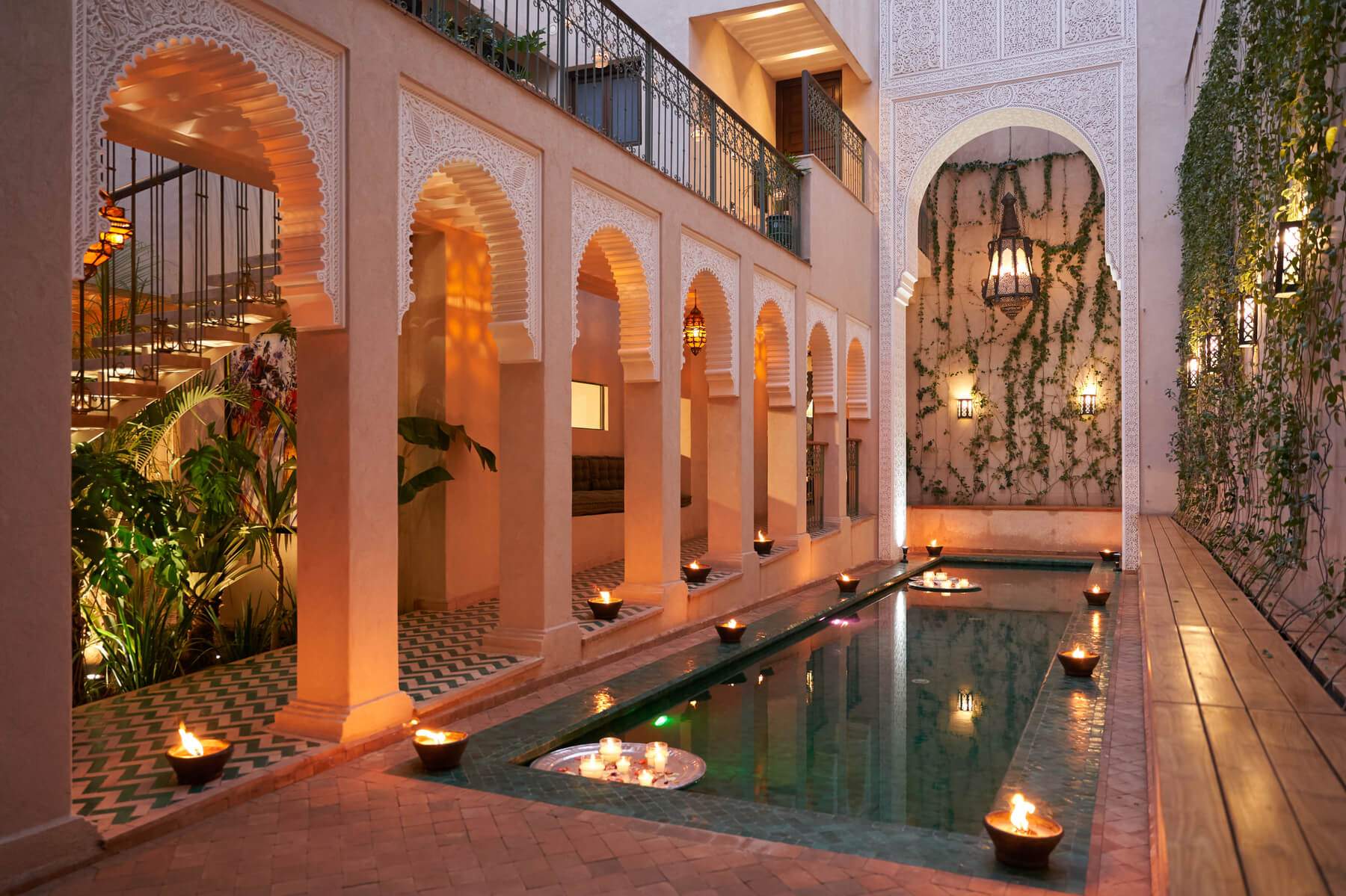 A beautifully lit swimming pool with a fountain and a patio with a view of the pool.