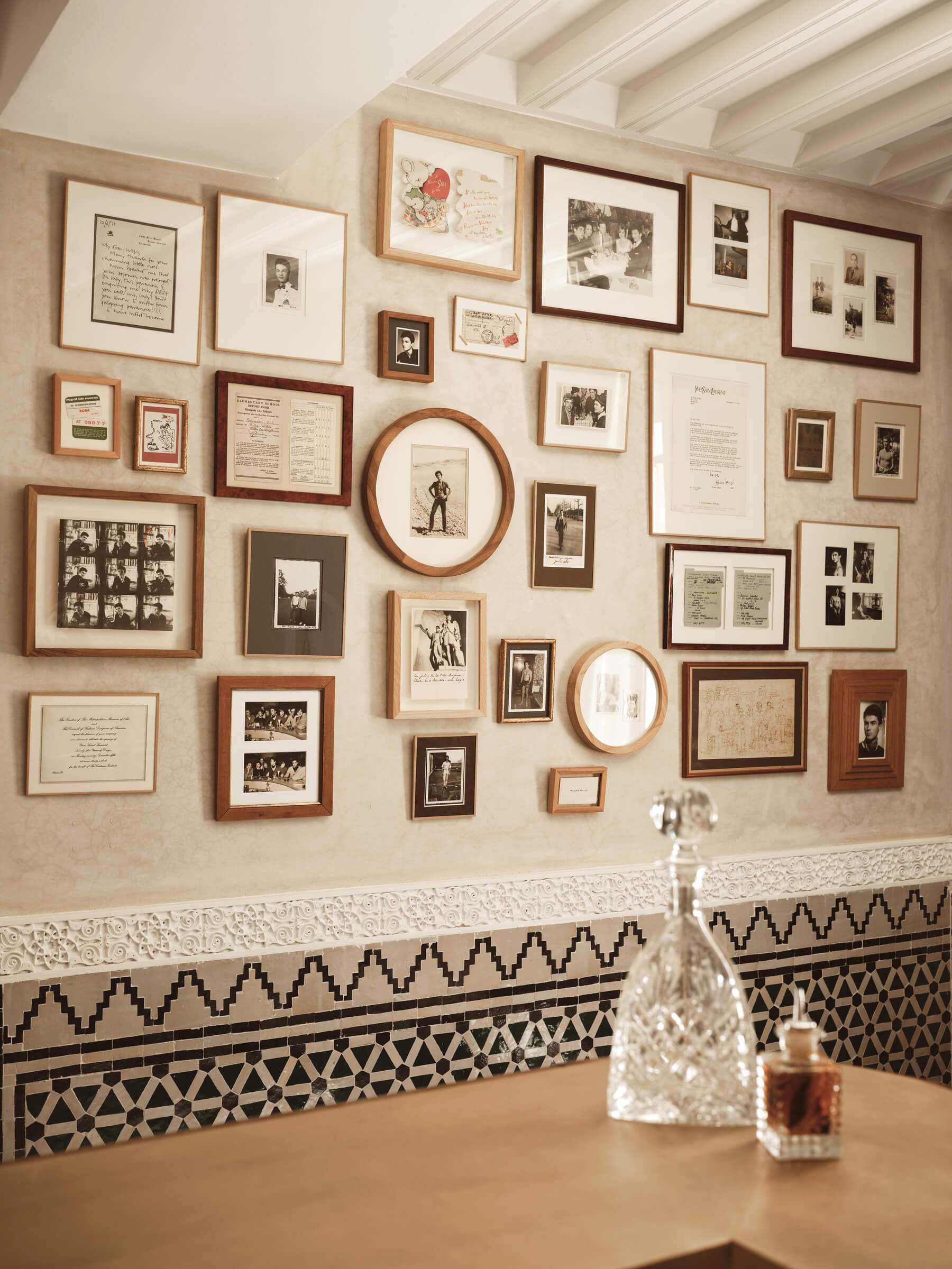 A wall full of pictures and a vase on a table.