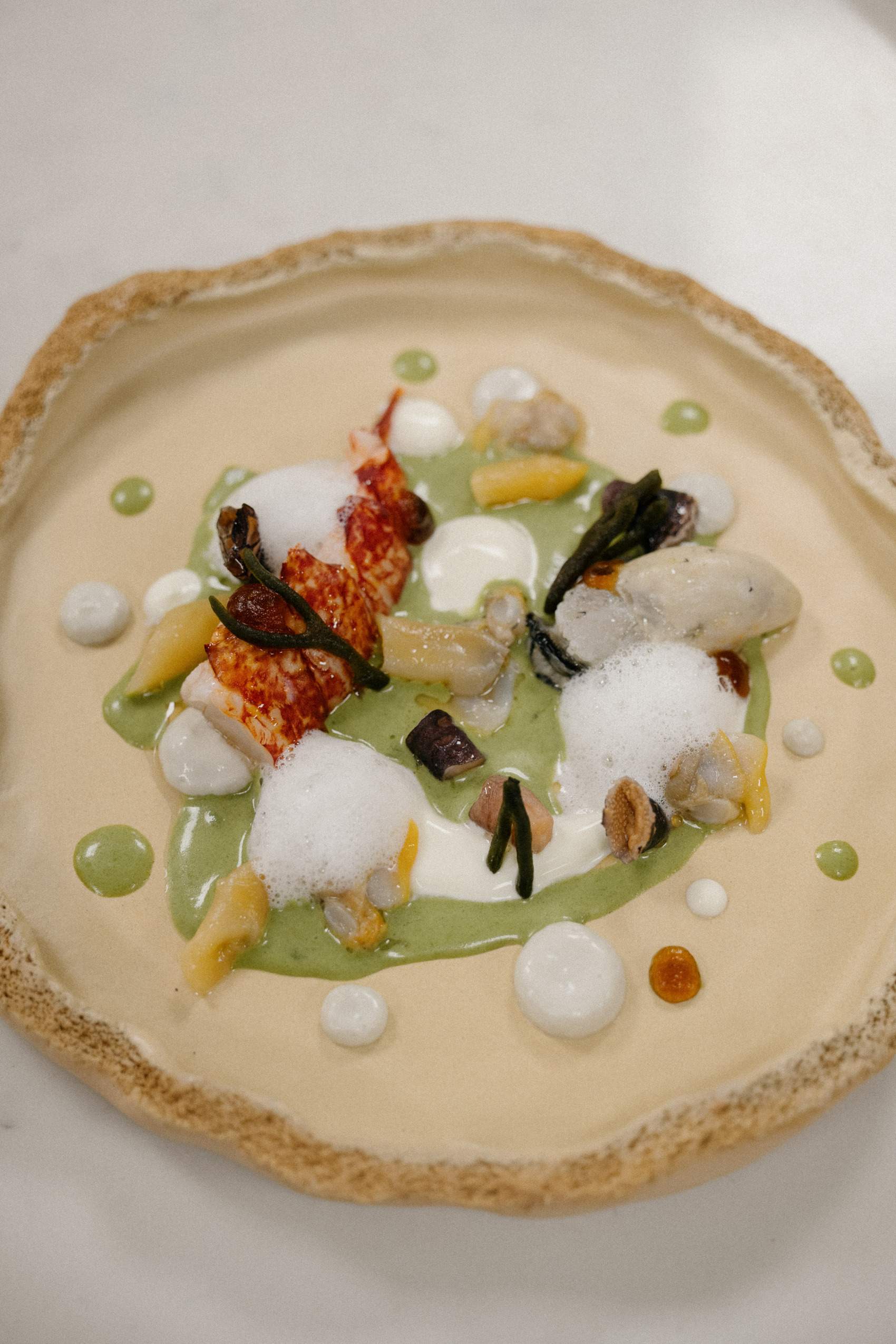 A plate of food with a lobster tail and other seafood items.