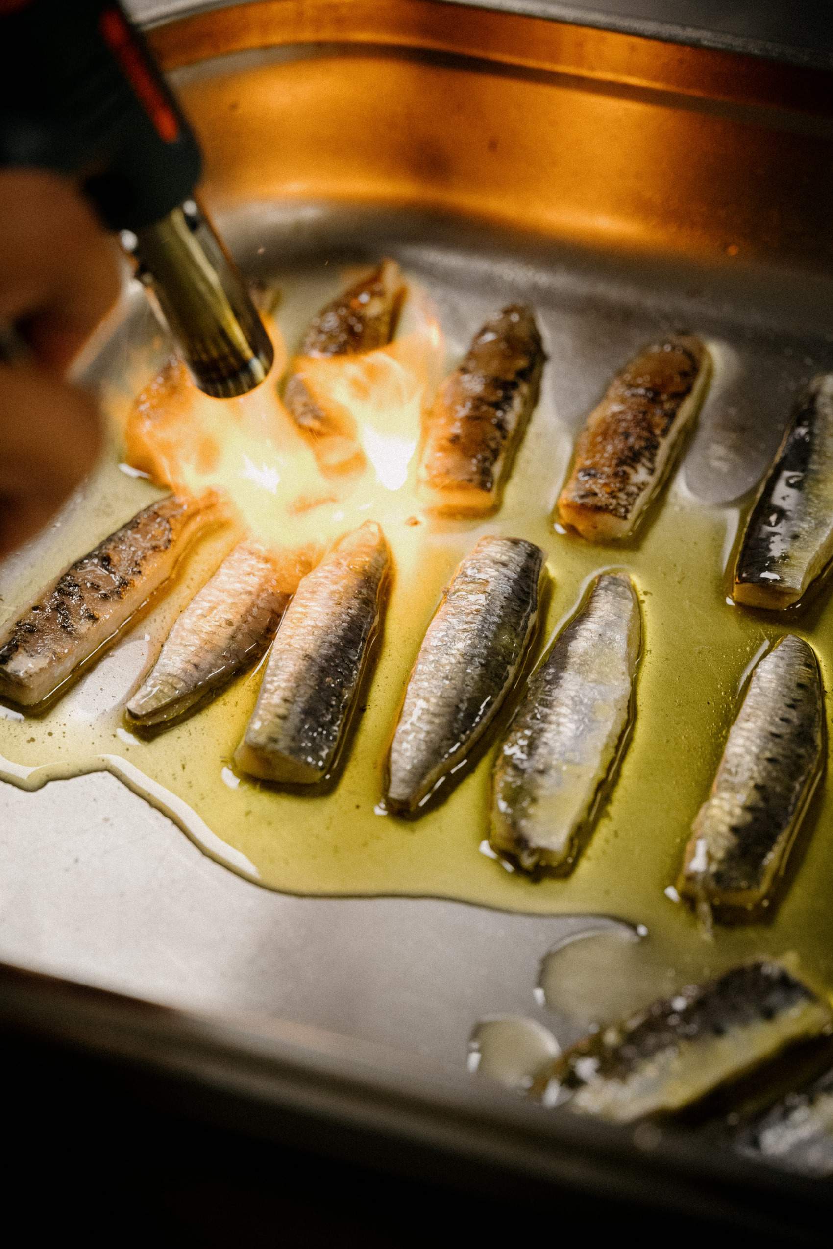A person is cooking fish on a stove.