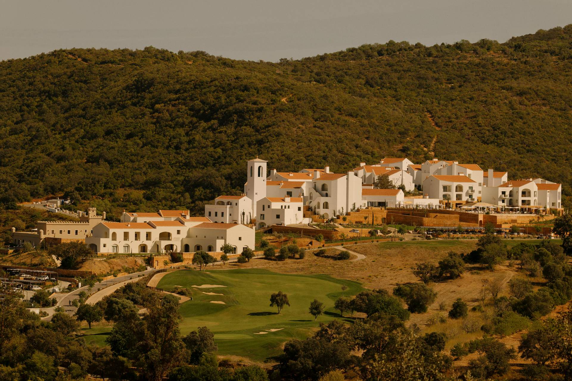 A golf course with a green course and a white building in the background.