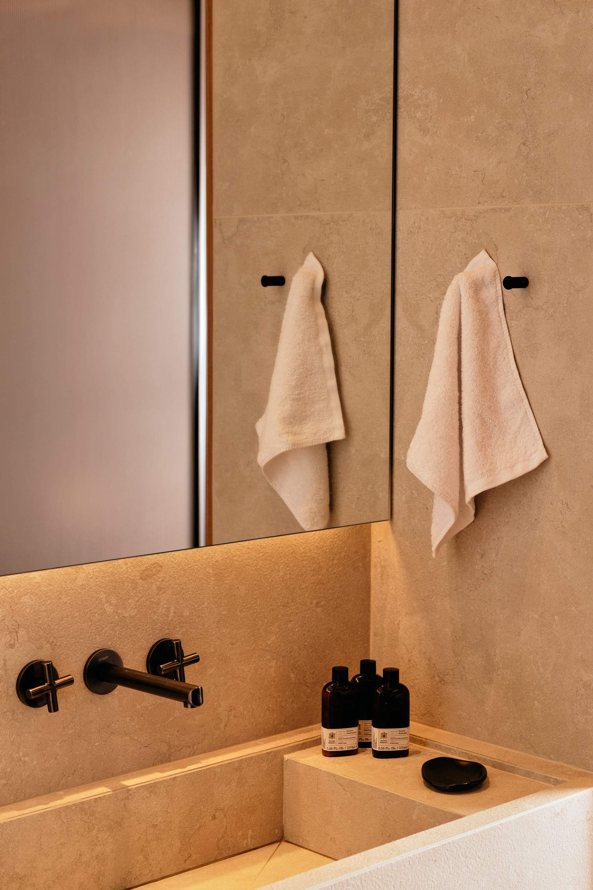 A bathroom with a mirror and two towels hanging on the wall.