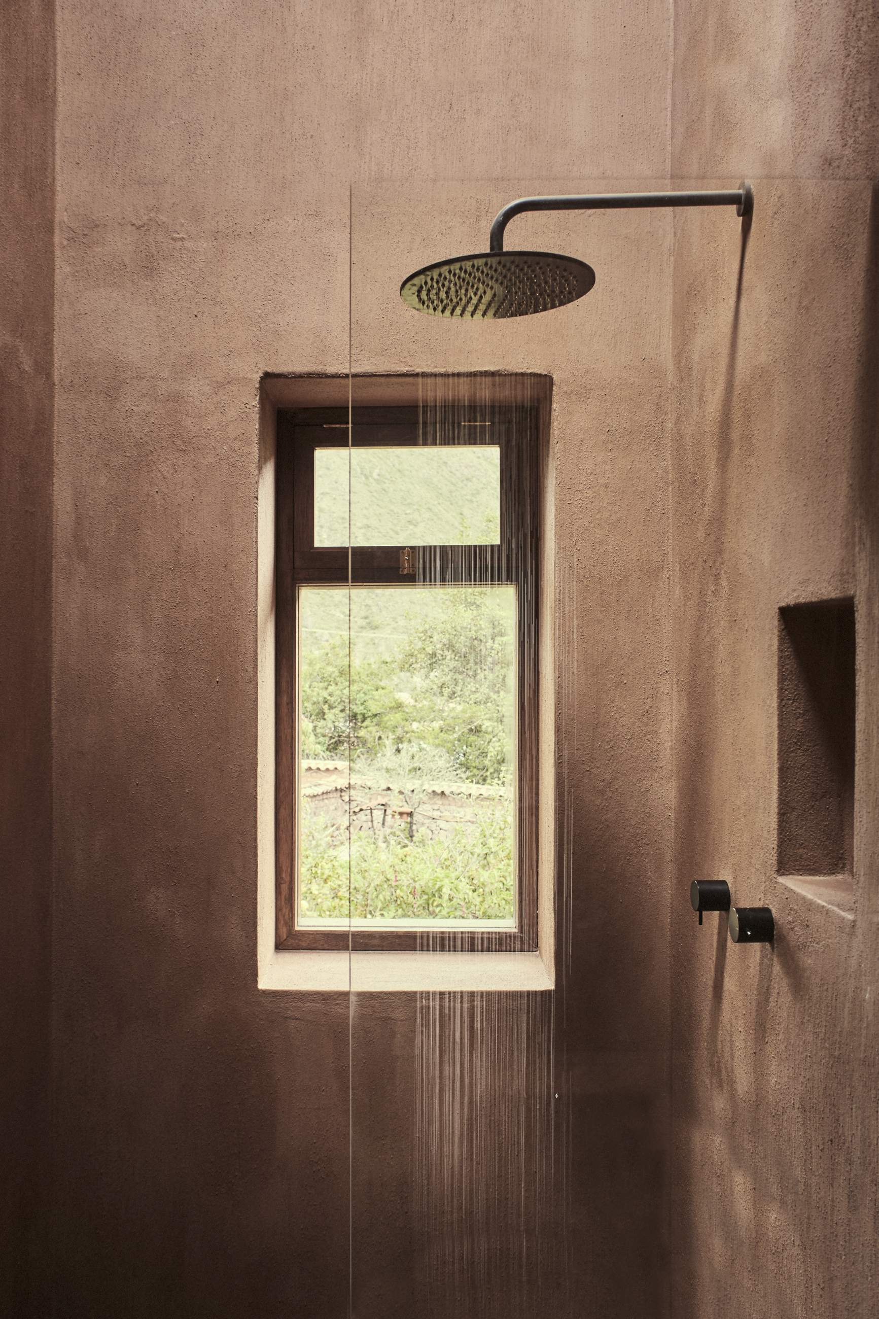 A shower with a window and a shower head.