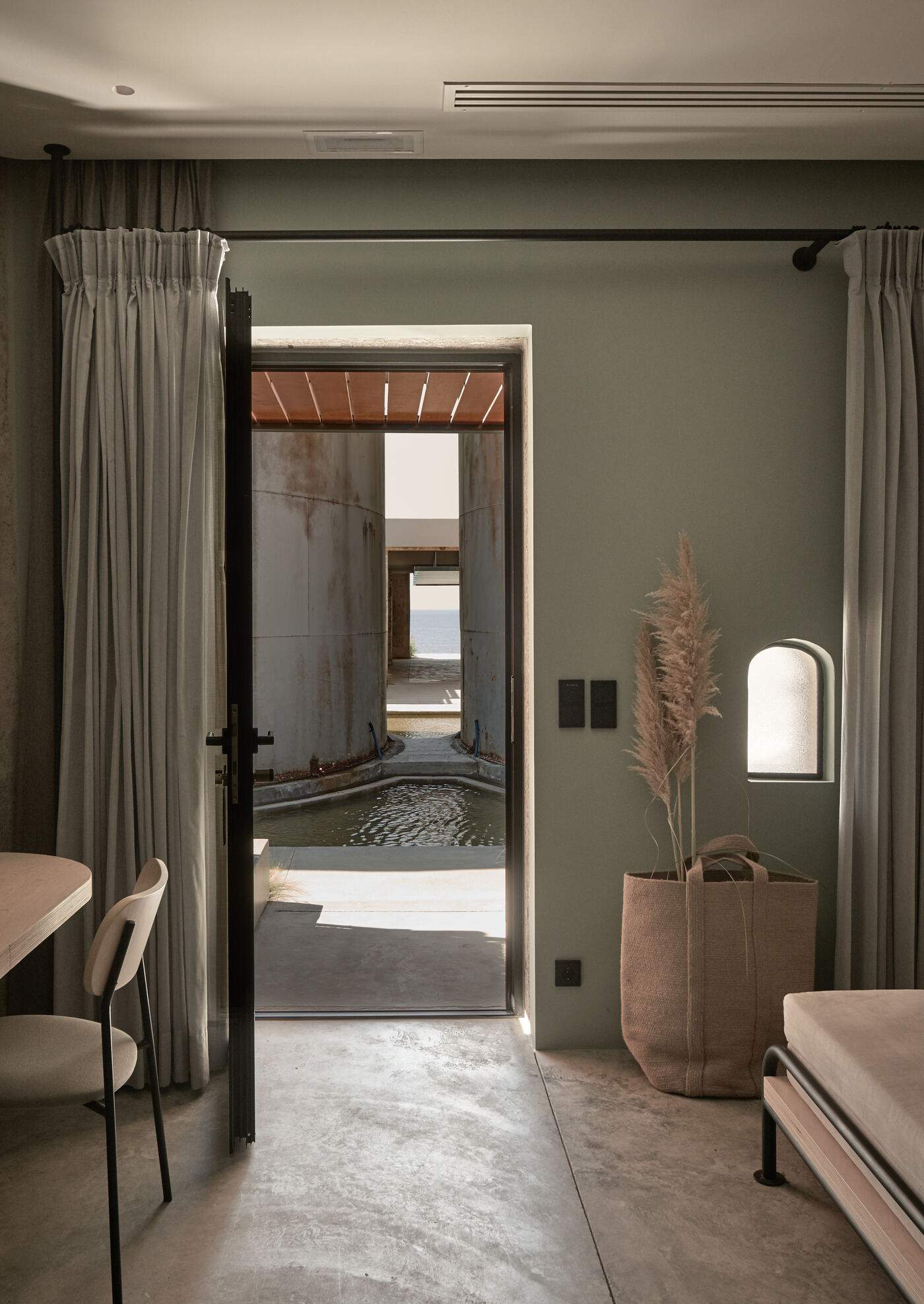 A doorway to a room with a pool and a plant.