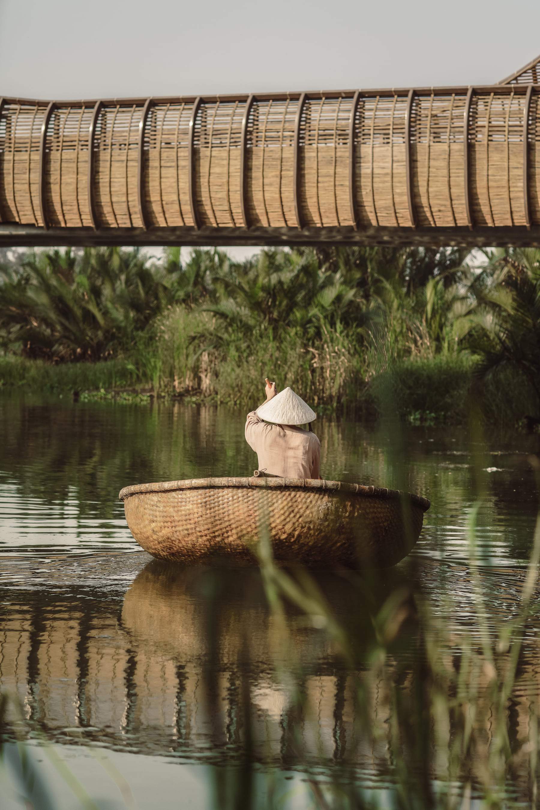 A person in a boat on a river with a hat on.