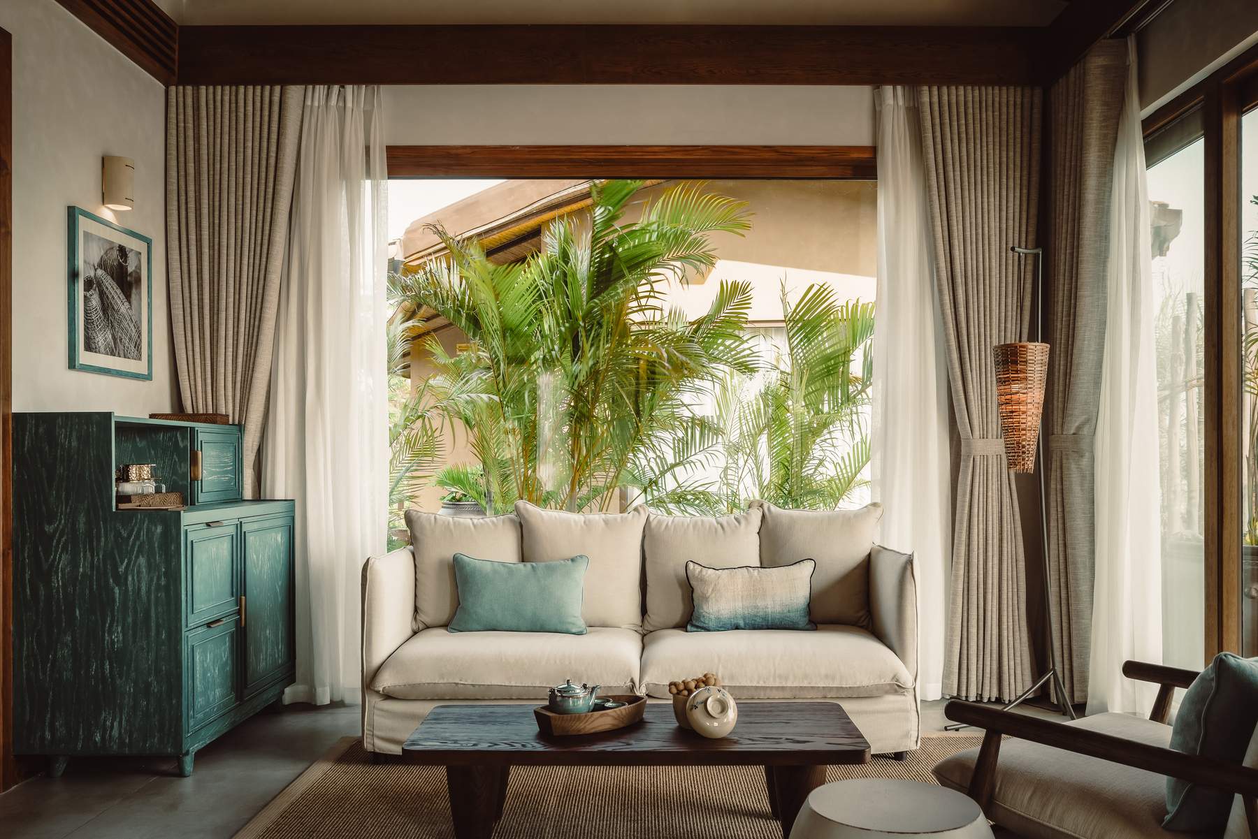 A white couch with pillows and a table with a bowl of fruit on it.