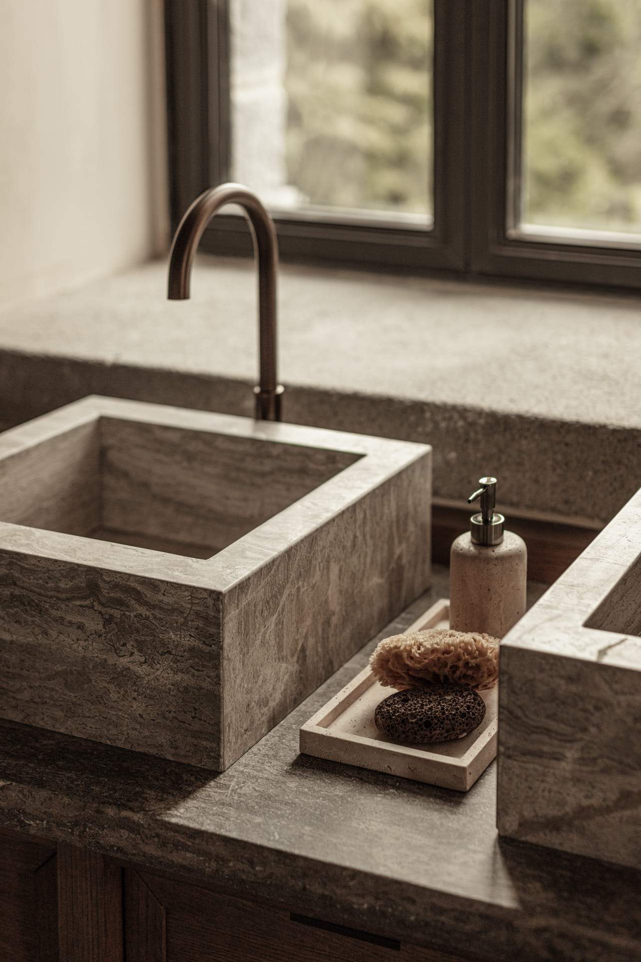 A sink with a faucet and a soap dispenser on the counter.