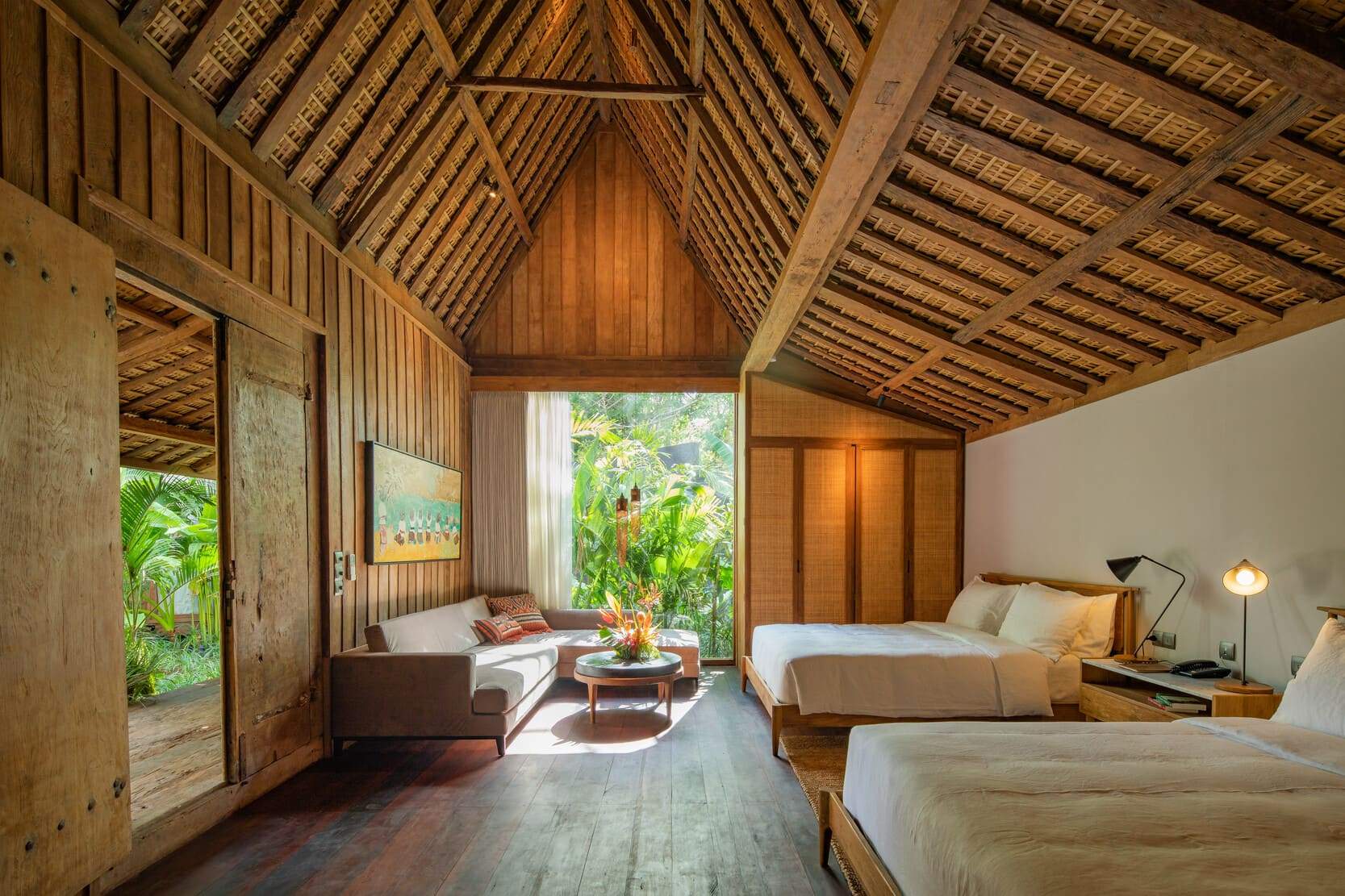 A bedroom with a wooden floor and a bed with white sheets.