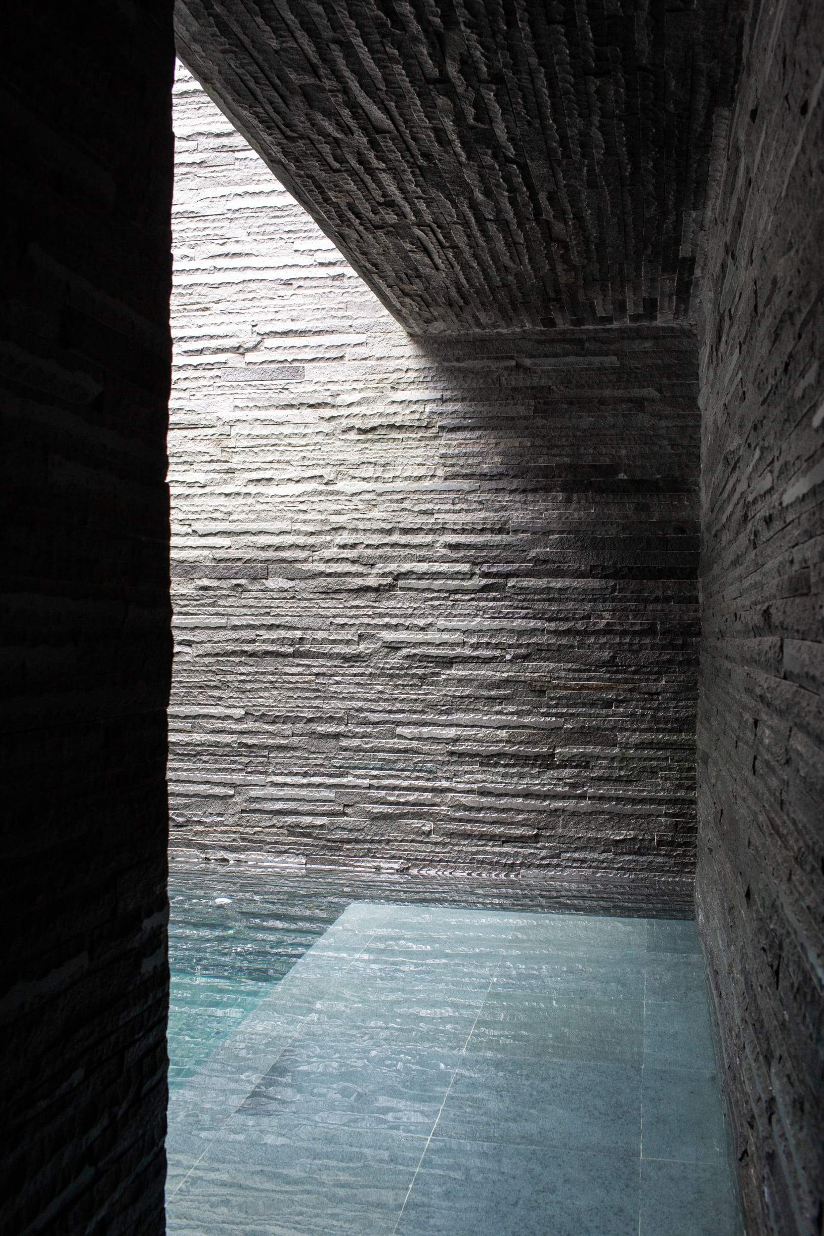 A dark room with a light shining through a stone wall.