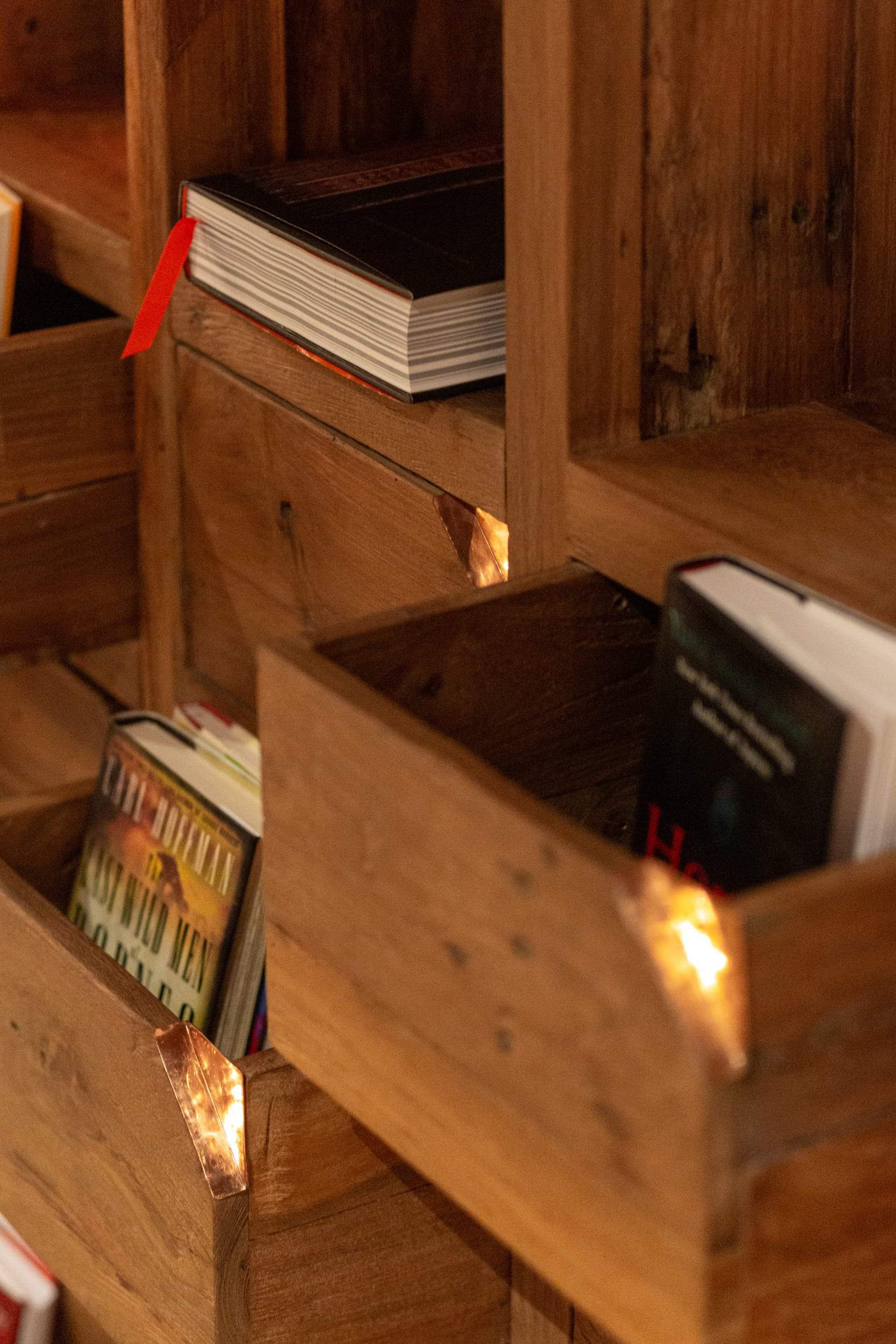 A wooden bookshelf with books and a red ribbon.