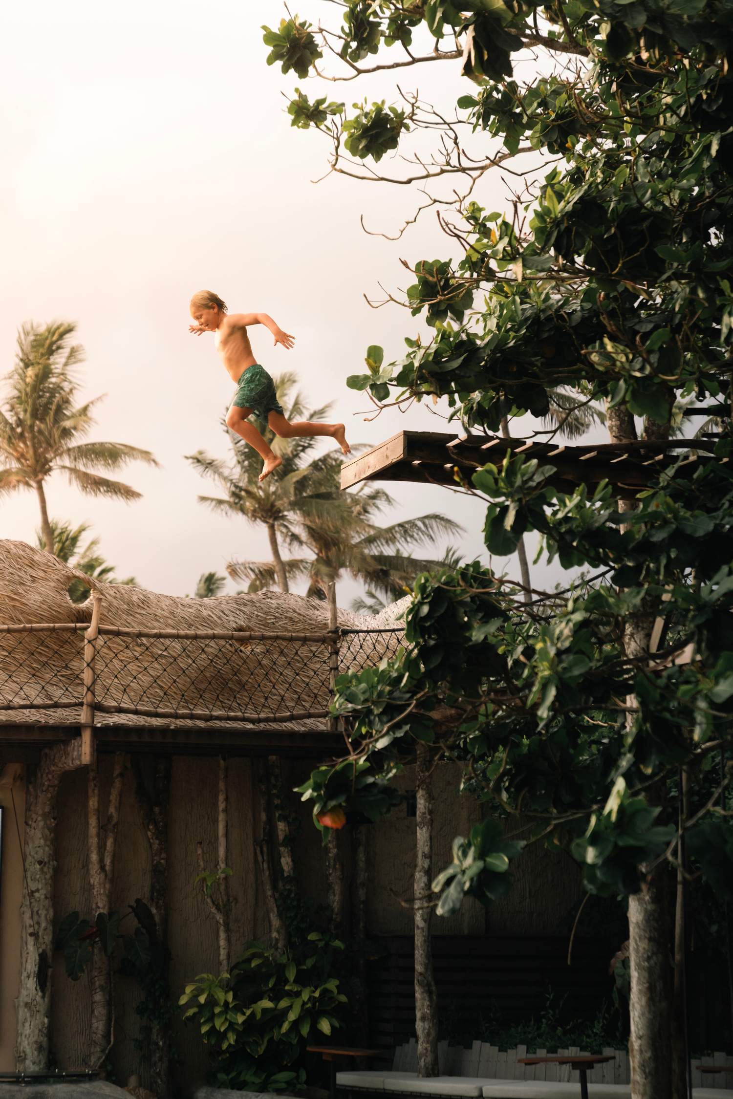 A boy is jumping off a wooden platform in the air.