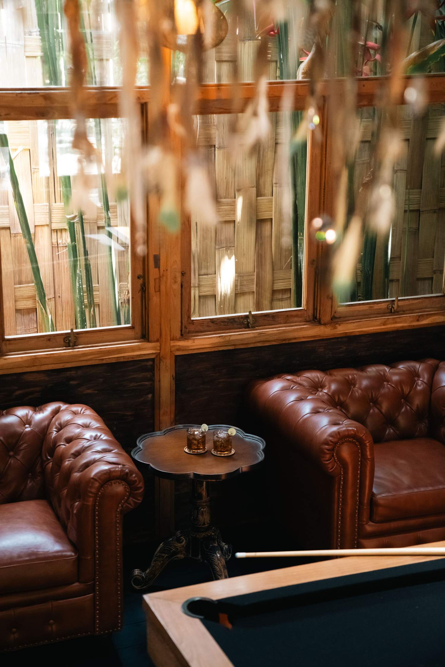 A brown leather couch with two glasses on a table in front of it.
