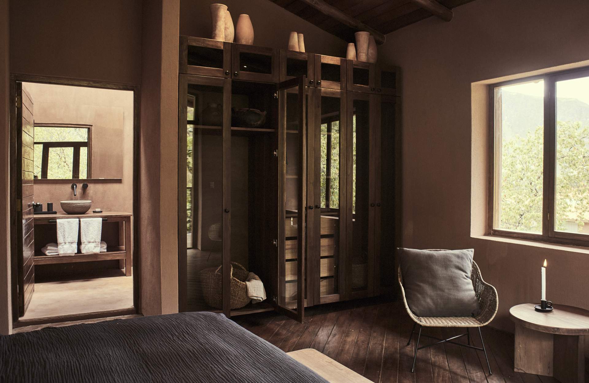 A bedroom with a bed, a chair, and a cabinet with a window.