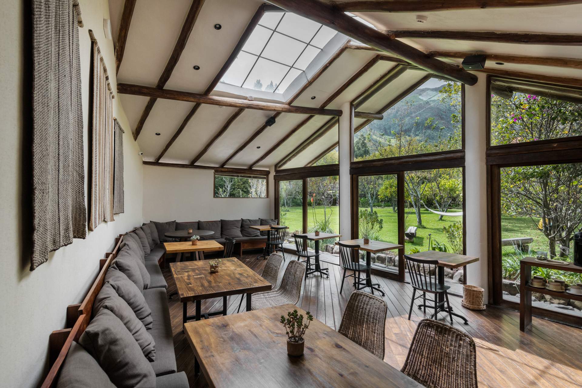 A large room with a wooden table and chairs, a couch, and a window.