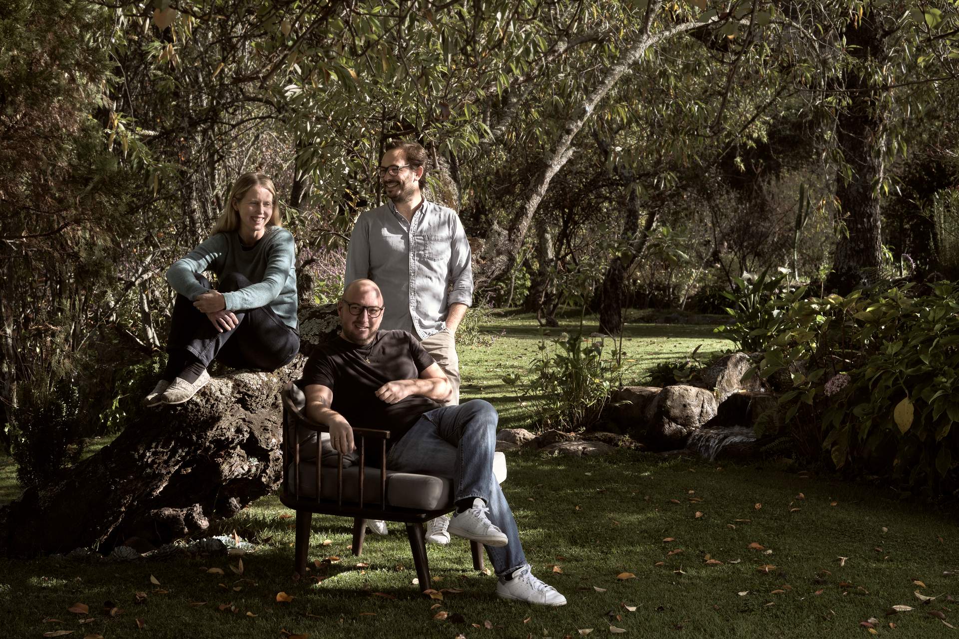 Three men sitting on a rock in a forest.