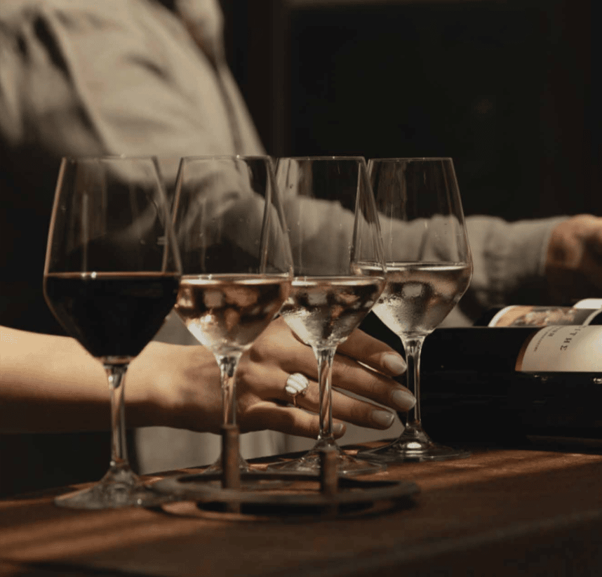 A person is holding a wine glass with a ring on their finger.