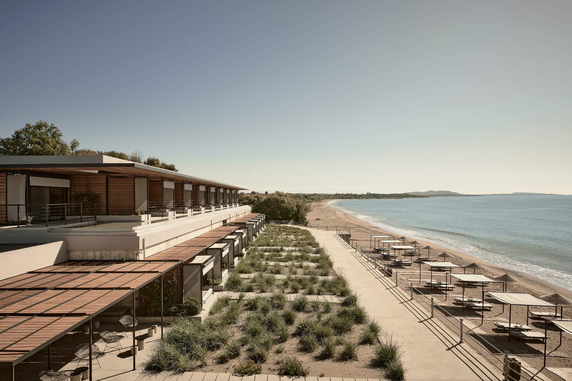 A beachfront resort with a row of chairs and umbrellas.