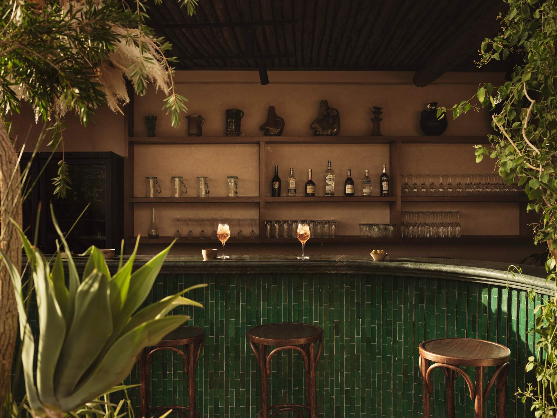 A bar with a green counter top and a row of stools.