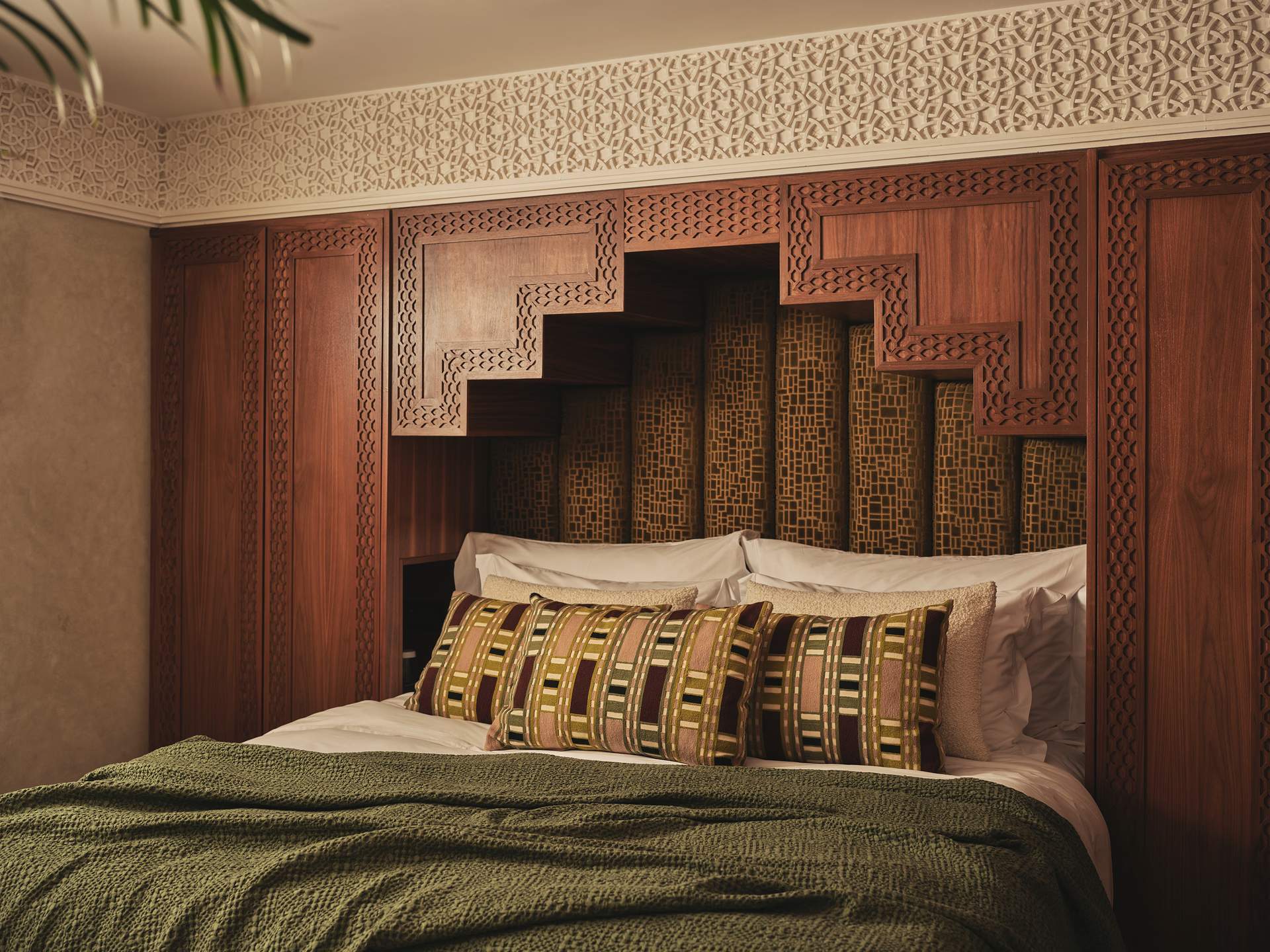 A bed with a brown wooden headboard and a green comforter.
