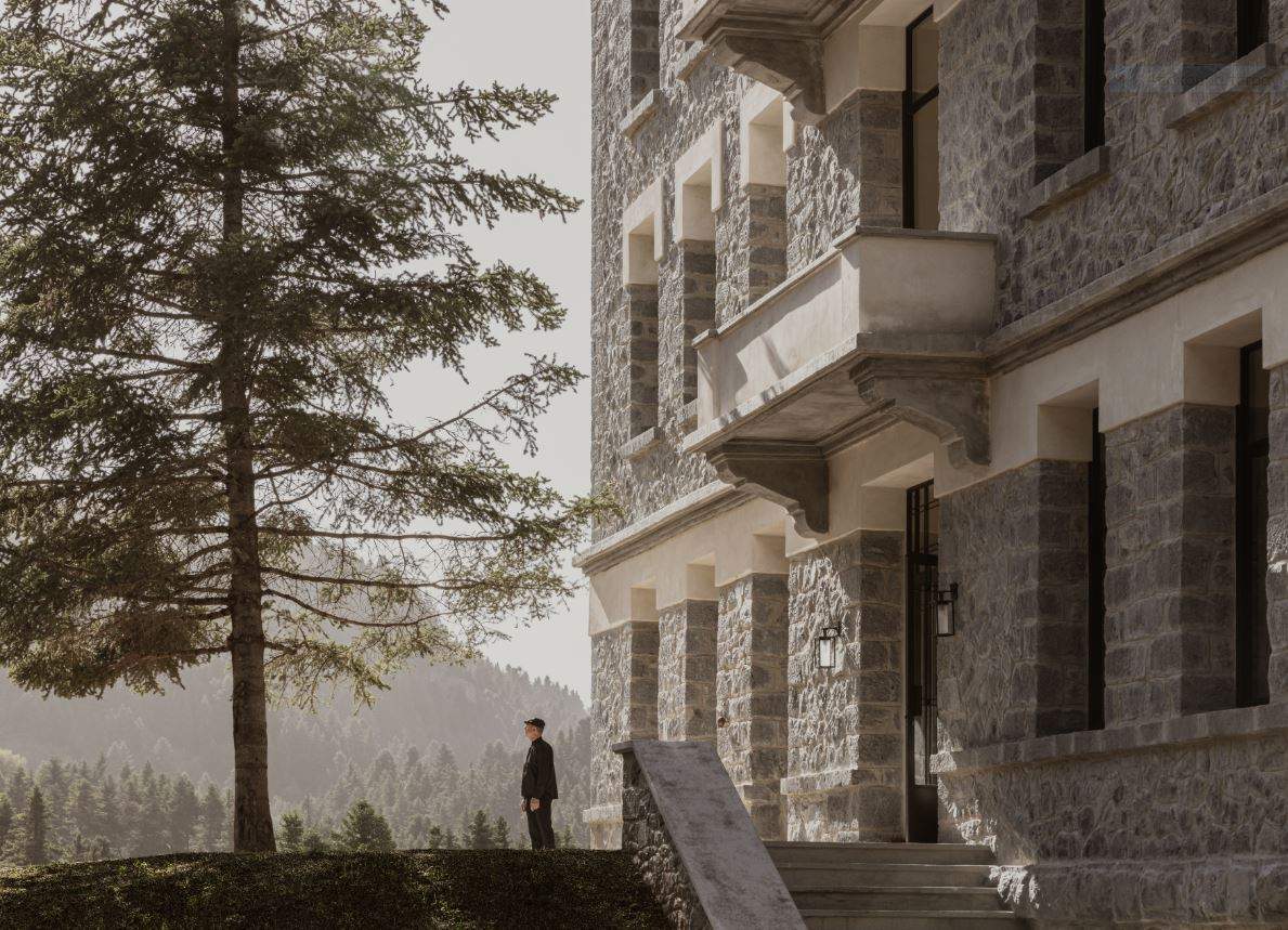 A man stands on a stone staircase in front of a large building.