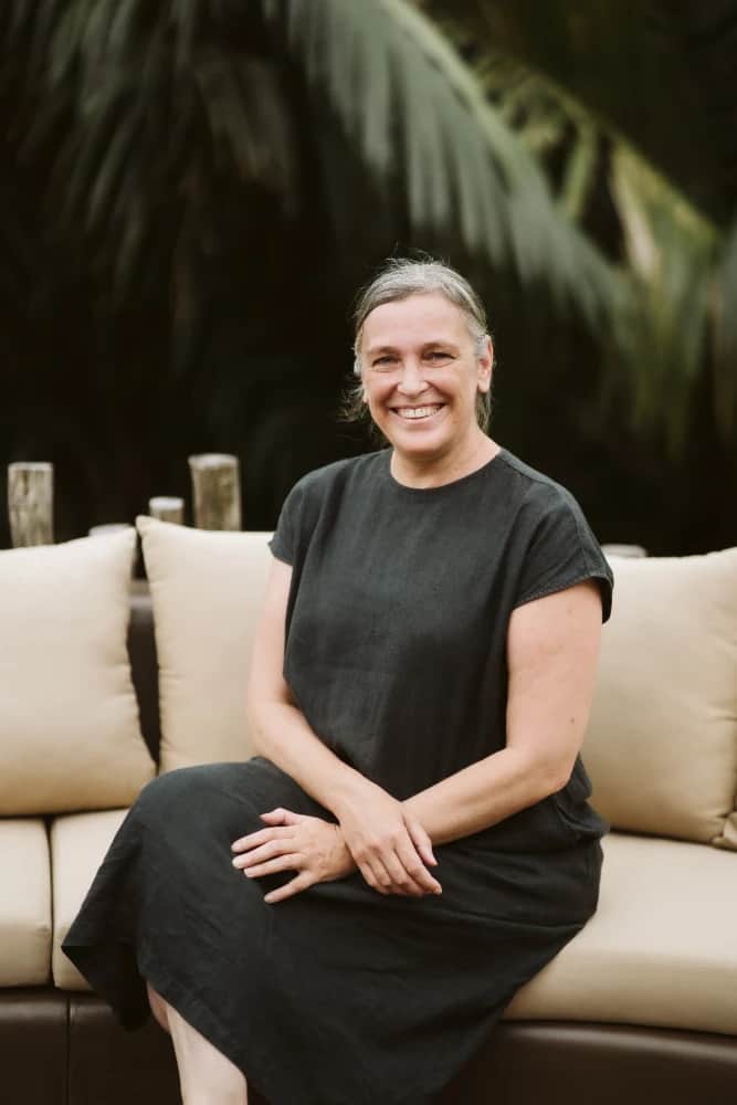 A woman wearing a black shirt and skirt is sitting on a couch.