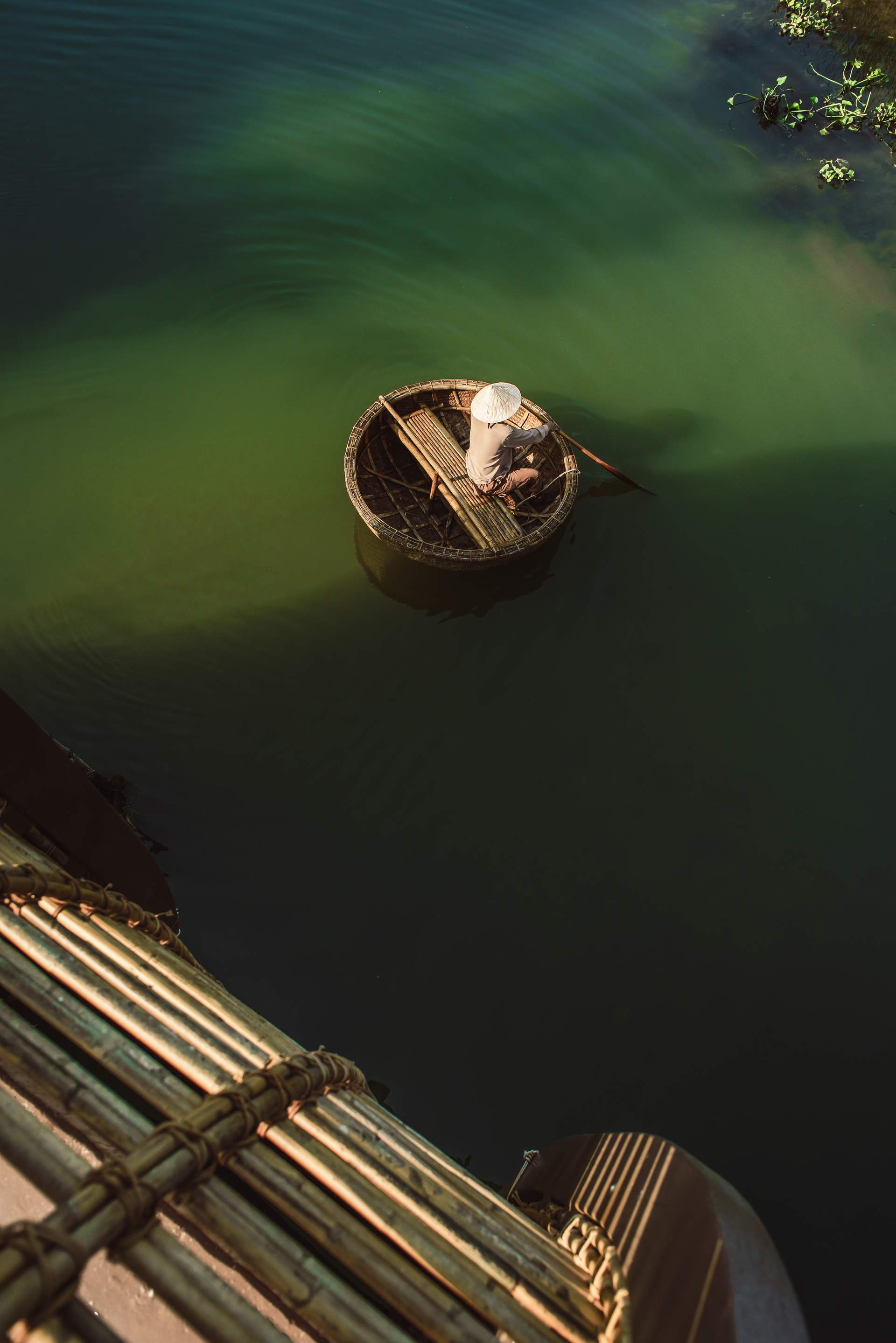 A man sits in a boat on a body of water.