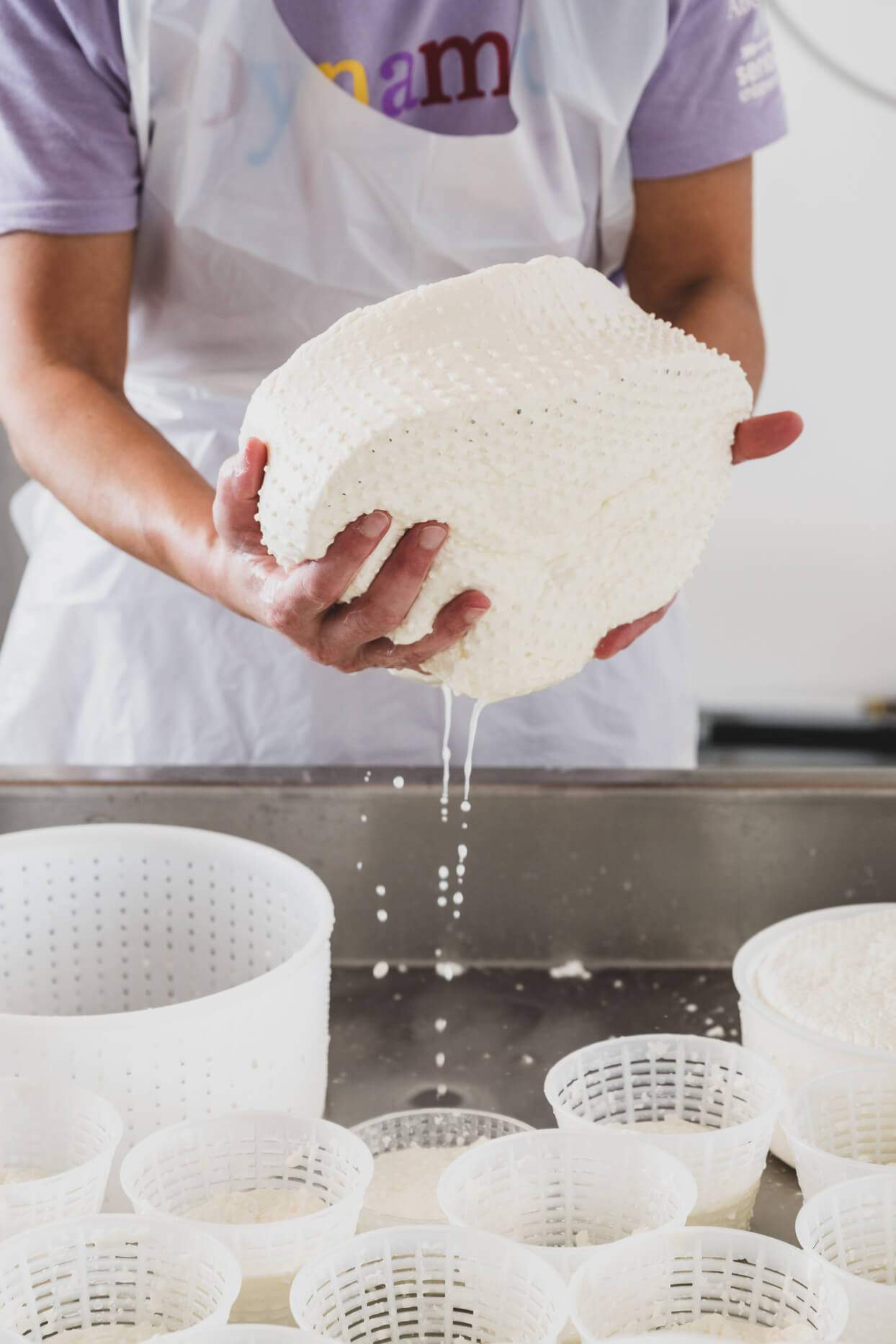 A person is holding a bowl of cheese that is dripping.
