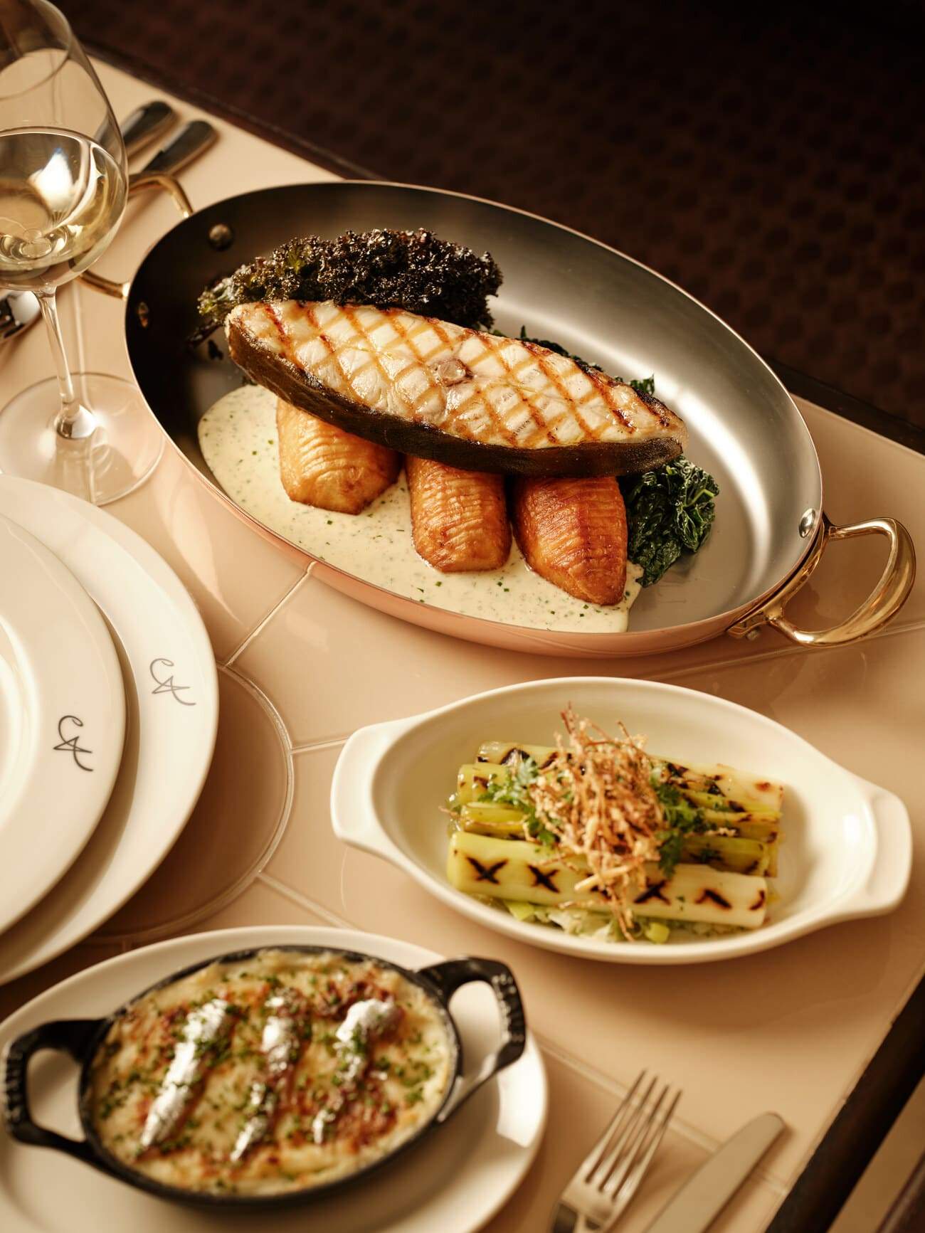 A table with a variety of food items, including fish, broccoli, and a vegetable dish.