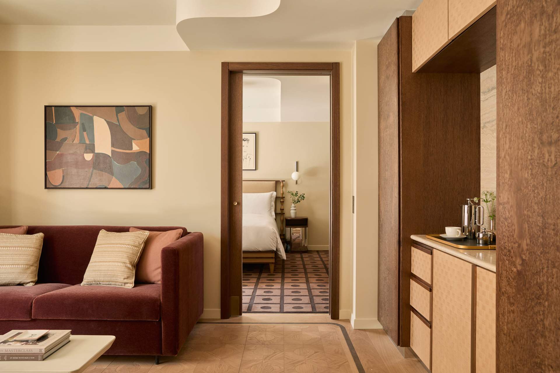 A living room with a brown couch and a bedroom with a bed.