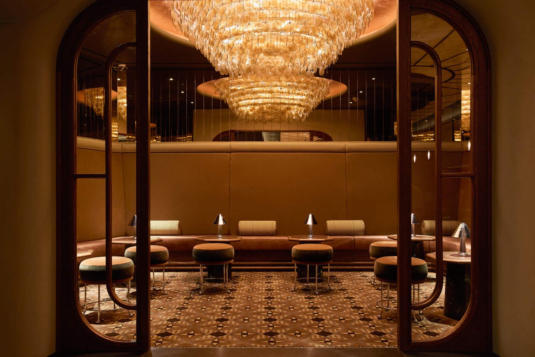 A large chandelier hangs above a group of couches and chairs in a room.