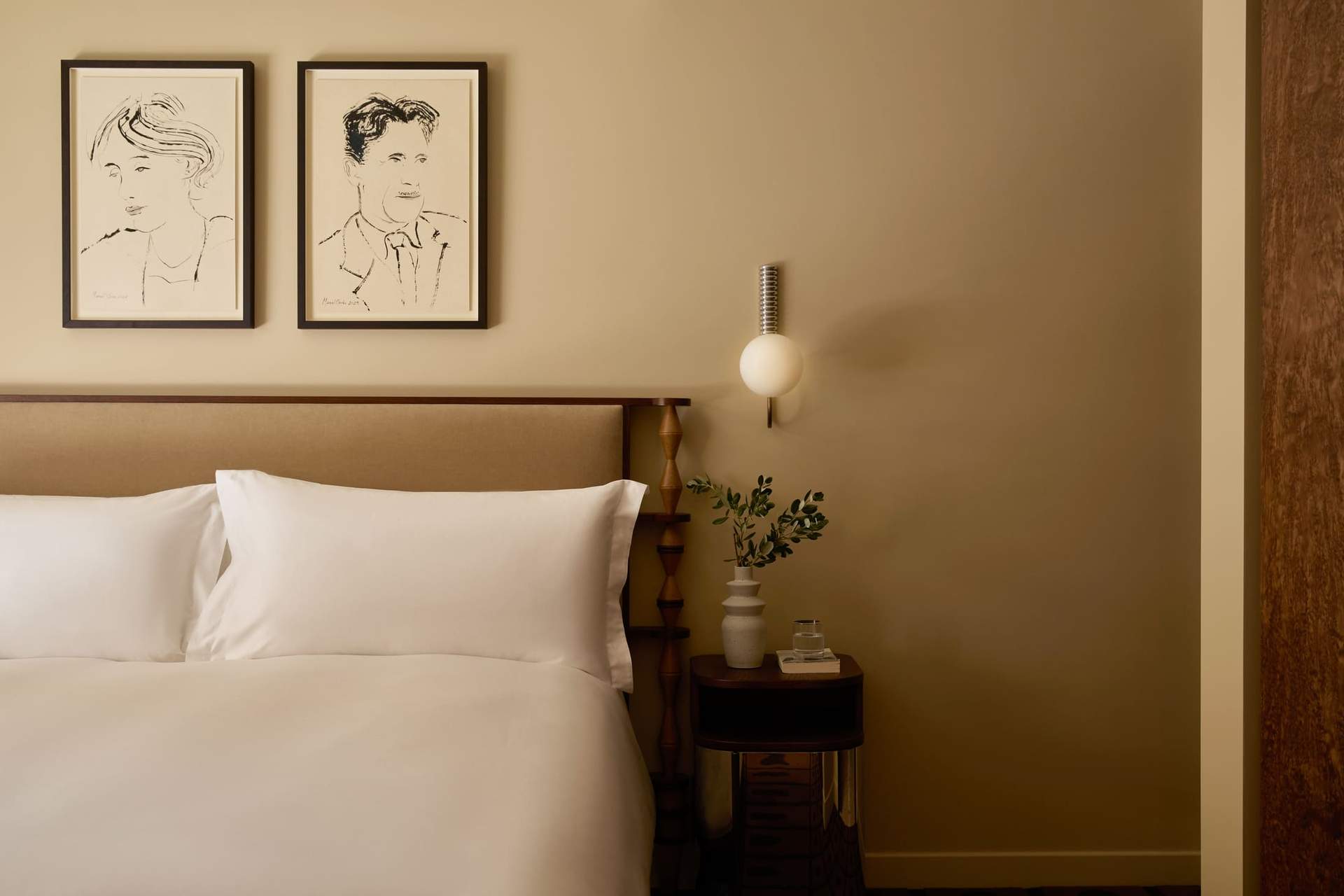 A bedroom with a bed and two pictures of men on the wall.