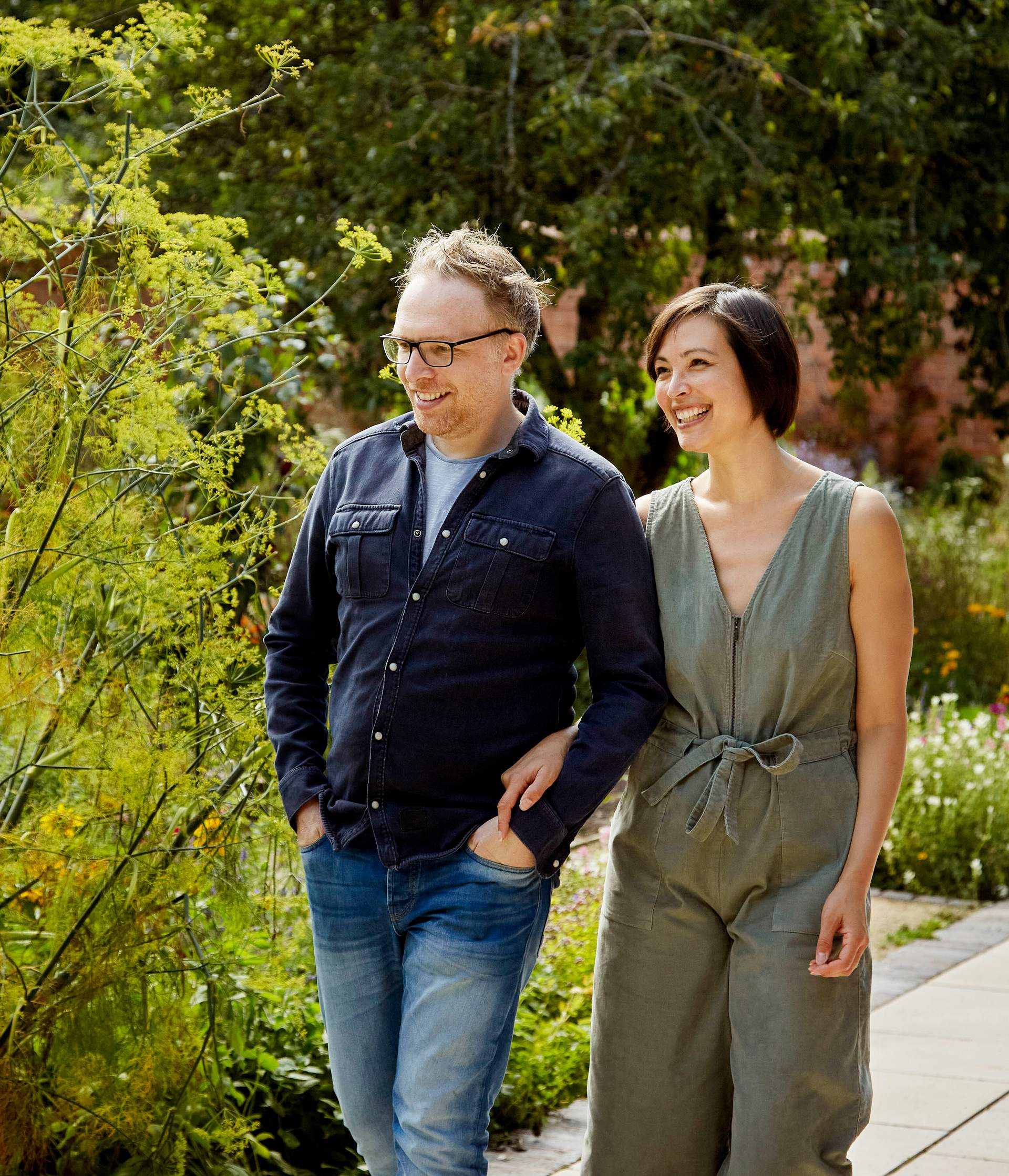 A man and woman walking together in a garden.