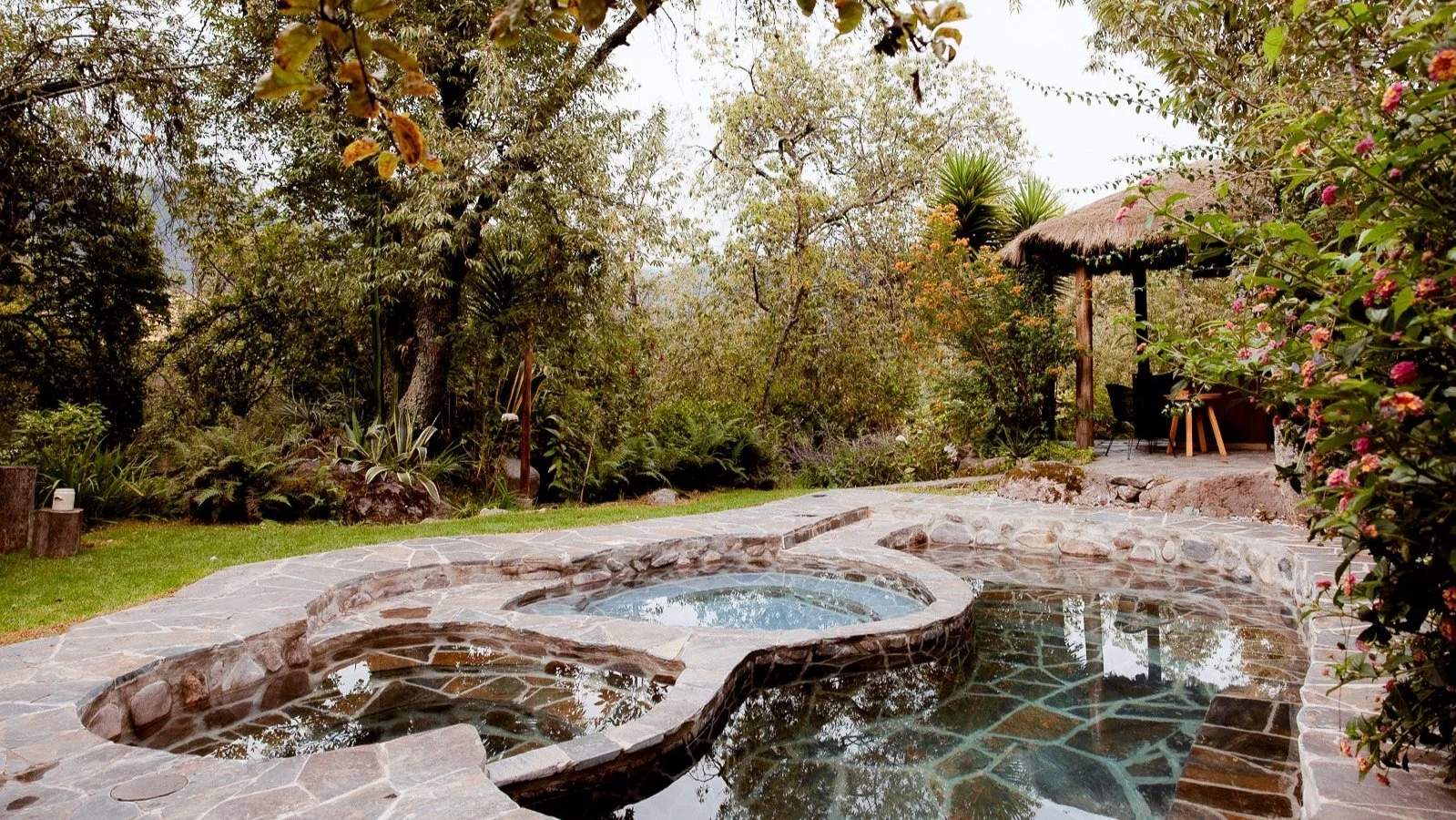 A swimming pool with a stone wall and a thatched roof.