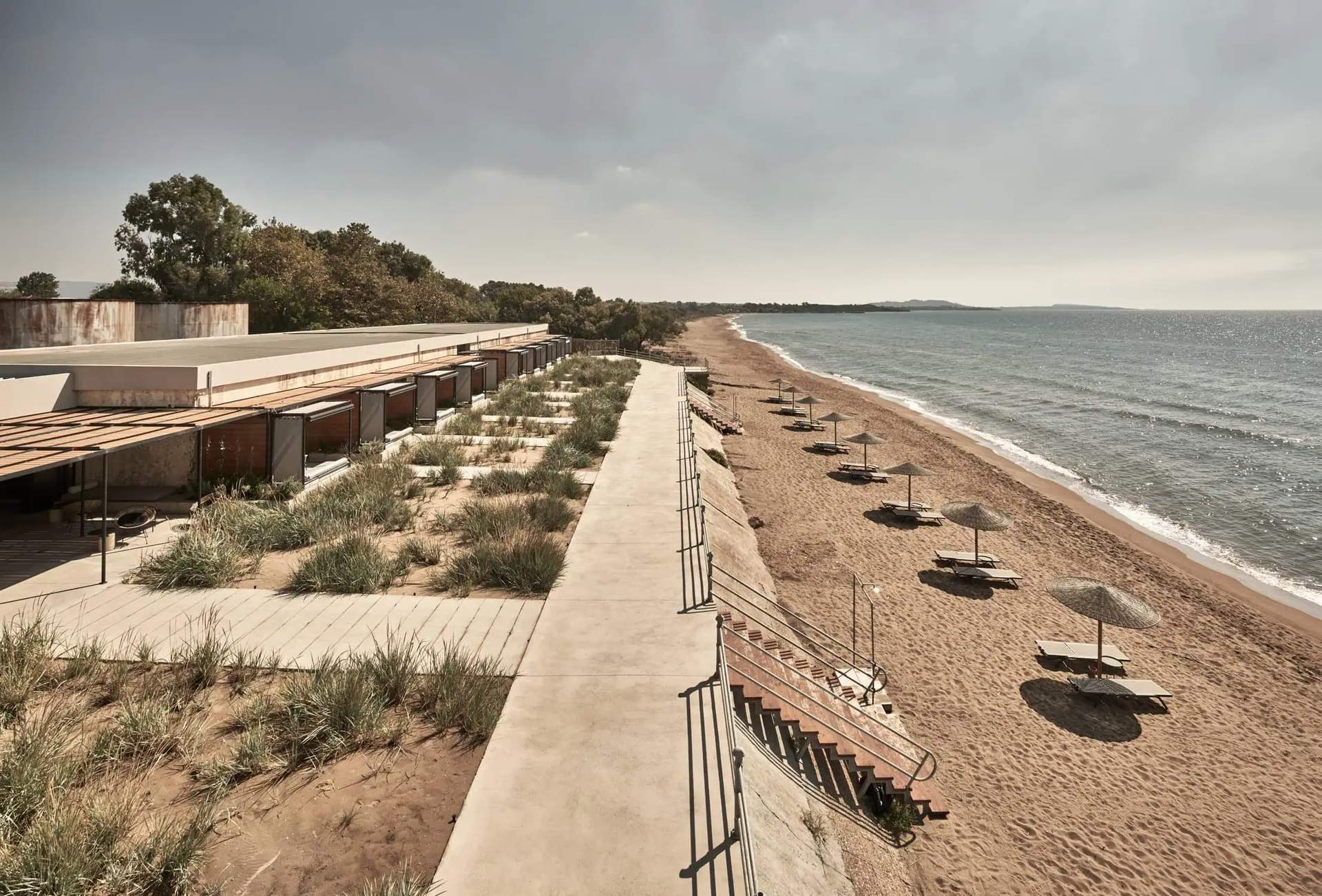 A beach with a row of umbrellas and chairs on the sand.